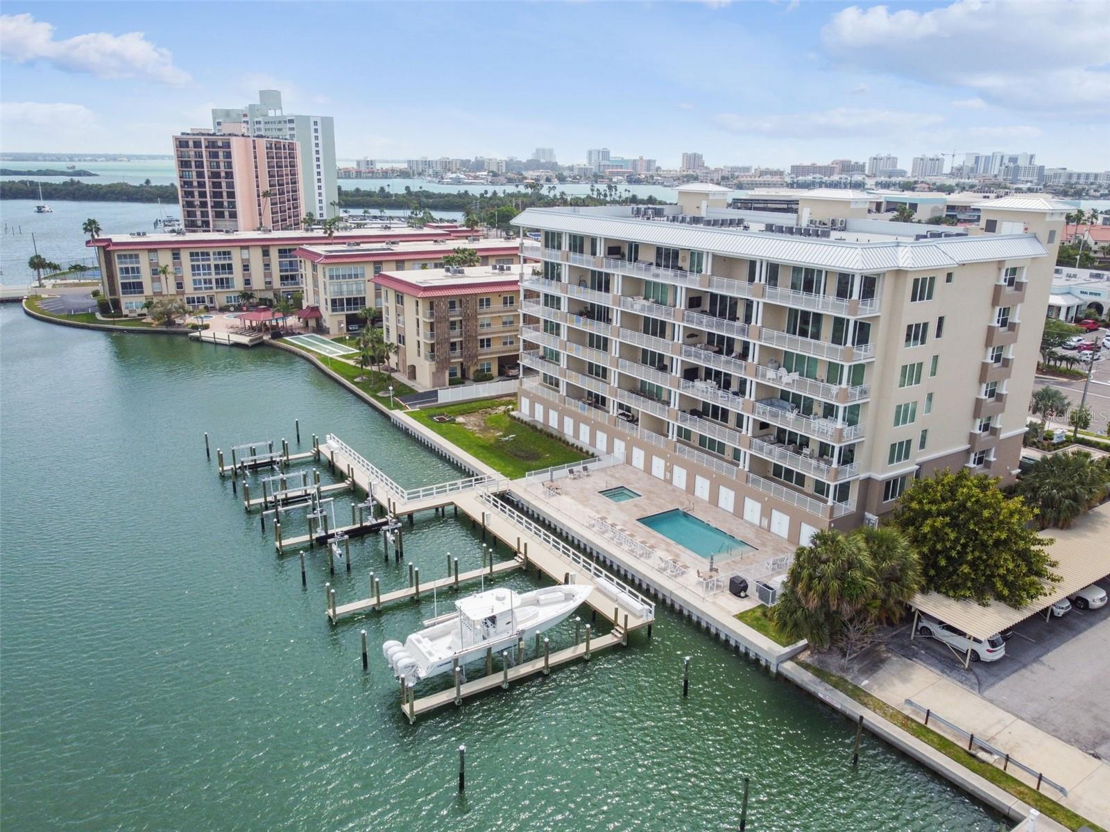 Stunning penthouse in Dolphin Harbour Condominiums, a newer addition to the coastal resort community of Island Estates, located between Clearwater and Clearwater Beach. This penthouse epitomizes upscale coastal living with its open floor plan designed to maximize breathtaking water views. It boasts three bedrooms and three and a half baths, along with a media room, all designed with luxurious living in mind. The living space extends into a 50-foot-wide balcony, accessible through eight-inch-high sliding glass doors, offering direct and unobstructed water views that invite the outdoors in. The expansive kitchen is a chef's dream, featuring top-of-the-line GE Cafe appliances equipped with WiFi for smart home integration. Quartz countertops, tile plank flooring, three skylights, and subtle under-cabinet lighting contribute to the kitchen's modern and airy feel. Baths are a sanctuary, with stone countertop surfaces and oversized frameless glass enclosures, blending functionality with elegance. The primary bedroom is a retreat unto itself, featuring a private balcony that looks out over the intercoastal waterways, providing a serene space to unwind. The unit includes a boat slip and cabana, enhancing a waterfront lifestyle. Additionally, there are two reserved parking spaces, with one located under the building for convenience. The community's amenities include a heated pool and spa located beachside. Additional features include an interior sound system for an immersive audio experience and designer two-panel interior doors that add to the unit's modern aesthetic. Living in Dolphin Harbour Condominiums means being part of a community that enjoys easy access to local shops, quick access to the pristine Clearwater Beach, and the convenience of a short drive from Tampa International Airport. This penthouse offers an unparalleled living experience, where luxury meets comfort in a setting that takes full advantage of its stunning coastal location.