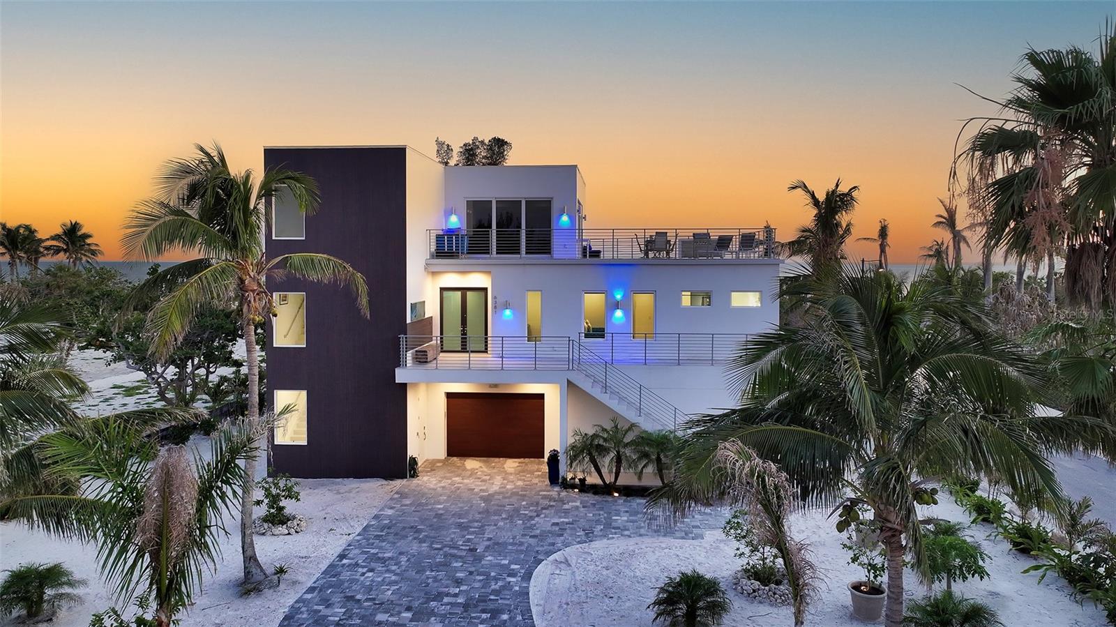One or more photo(s) has been virtually staged. Welcome to a once-in-a-lifetime opportunity to own a sleek, modern coastal estate on one of Longboat Key’s most coveted stretches of sand. Perfectly situated on a rare double lot on the beach side of Gulf of Mexico Drive, this architectural gem incorporates uninterrupted, panoramic views of the Gulf. This completely turnkey furnished 4,420 square foot home has 4 bedrooms, 5 bathrooms and includes many upgrades showcasing incredible style. With nothing ever to be built in front, those golden sunsets and turquoise seas can be yours to savor forever. Built in 2021 with no expense spared, this home is a fortress of strength. Designed for durability by a structural architect, this home is constructed entirely of concrete utilizing sheer walls and concrete block combined with over-engineered pilings for peace of mind. Reglet trim has been achieved by utilizing metal steel framing , providing longevity and function. Inside, dramatic Euro-wall sliders blur the boundaries between indoors and outdoors, leading to a wraparound terrace that offers sweeping 260-degree views. A stunning elevated infinity-edge pool and spa, an outdoor shower and a fire table provide endless enjoyment. Level 5 drywall, oversized porcelain tile floors, and high design finishes elevate every corner. The main living level features a dazzling chef’s kitchen with European lacquer cabinetry, quartzite counters, and top-of the-line appliances: a 48” Sub-Zero fridge, 48” gas range, two ice makers, wine fridge, microwave drawer, natural gas service and more. Lutron LED lighting enhances the crisp, contemporary ambiance. The outdoor living is equally luxurious utilizing matching porcelain tile and a walnut-lined covered terrace to flow seamlessly from the interior. The top floor is a true penthouse master suite, leading to a self-contained oasis. The spa-like bathroom includes a soaking tub, a huge walk in shower and Gulf views from every room. An additional 1,150 square foot upper patio deck is framed by huge sliders allowing true indoor/outdoor living. In addition there is a second laundry room and kitchenette creating an amazing sanctuary. Whether used as a private refuge or separate guest quarters, this space can be closed off from the rest of the home, allowing the second floor, which includes 3 bedrooms and 3.5 baths, to be independently rented while preserving your own private haven. Three garages accommodate up to 9 vehicles, a gym and recreational toys. Leading outside is a large open area providing room to add a pickleball court or putting green. Beyond is over an acre of public land owned by the town of Longboat Key insuring your forever Gulf views. Additional perks include an elevator, two-zone A/C, dual laundry setups, gas tankless water heater, and electronic shades throughout. Currently operating as The Sea Grape Inn, this home offers income potential without sacrificing privacy, making it a rare hybrid of luxury retreat and smart investment. Step from your door to the sugar-white sands of Longboat Key and experience the pinnacle of Gulf-front living.
