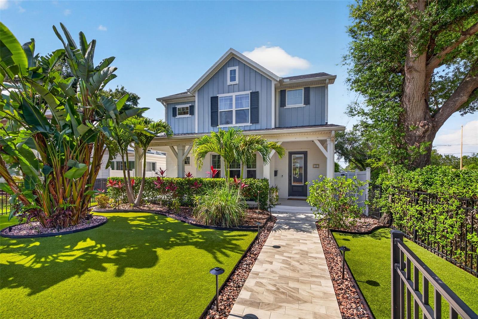 Welcome to the perfect blend of modern farmhouse elegance, effortless luxury, and walkable St. Petersburg living. Nestled in the highly sought-after Five Points neighborhood, this exceptional residence places you just moments from Coffee Pot Bayou, Trader Joe's, local shops, restaurants, and all the exciting growth and energy transforming this vibrant area. Why wait for new construction when you can move right into a home that feels even better than new? Newly built in 2021 and thoughtfully enhanced by its current owners, this meticulously maintained home offers truly turnkey living from day one. Follow the paver pathway through the lush tropical landscaping and gated front yard featuring low-maintenance artificial turf before arriving at the inviting front porch, the perfect place to unwind and connect with neighbors on a beautiful Florida evening. Step inside and discover a light-filled open floor plan designed for both everyday comfort and effortless entertaining. A stunning sightline extends through the home to the backyard oasis beyond, while a private study or guest bedroom with French doors provides flexibility for today's lifestyle. The spacious family room showcases soaring ceilings, abundant natural light, and seamless flow into the chef-inspired kitchen featuring a gas cooktop, built-in ovens with convection, steam, and microwave capabilities, quartz countertops, stainless steel appliances, wine refrigerator, ceiling-height solid wood cabinetry, designer tile backsplash, butler's pantry, oversized walk-in pantry, and a large island ideal for gathering family and friends. Upstairs, a versatile loft offers additional living space and could easily be converted into another bedroom if desired. Two guest bedrooms, a full bath, and a conveniently located laundry room lead to the impressive primary suite retreat featuring automated blackout shades, a spa-inspired bath with stylish black-and-white tile flooring, shiplap accent wall, dual vanities, and a custom walk-in closet with built-in shelving. Step outside and experience your own private tropical resort where a sparkling pool, relaxing spa, sun shelf, covered porch, lush landscaping, and maintenance-free turf create the ultimate setting for year-round Florida living. Pool LED lighting and spa functions are conveniently controlled through the Aqualink app, making every day feel like a vacation. Additional highlights include a detached two-car garage with alley access that has already been engineered to support a future second-story addition, impact-rated windows and doors, and a fully integrated smart home system that controls the door locks, lighting, HVAC, garage doors, and security system with three cameras. Beautifully designed, thoughtfully upgraded, and ideally located, this exceptional Five Points residence offers the rare opportunity to enjoy modern construction, smart-home convenience, resort-style outdoor living, and one of St. Petersburg's most desirable and walkable neighborhoods.