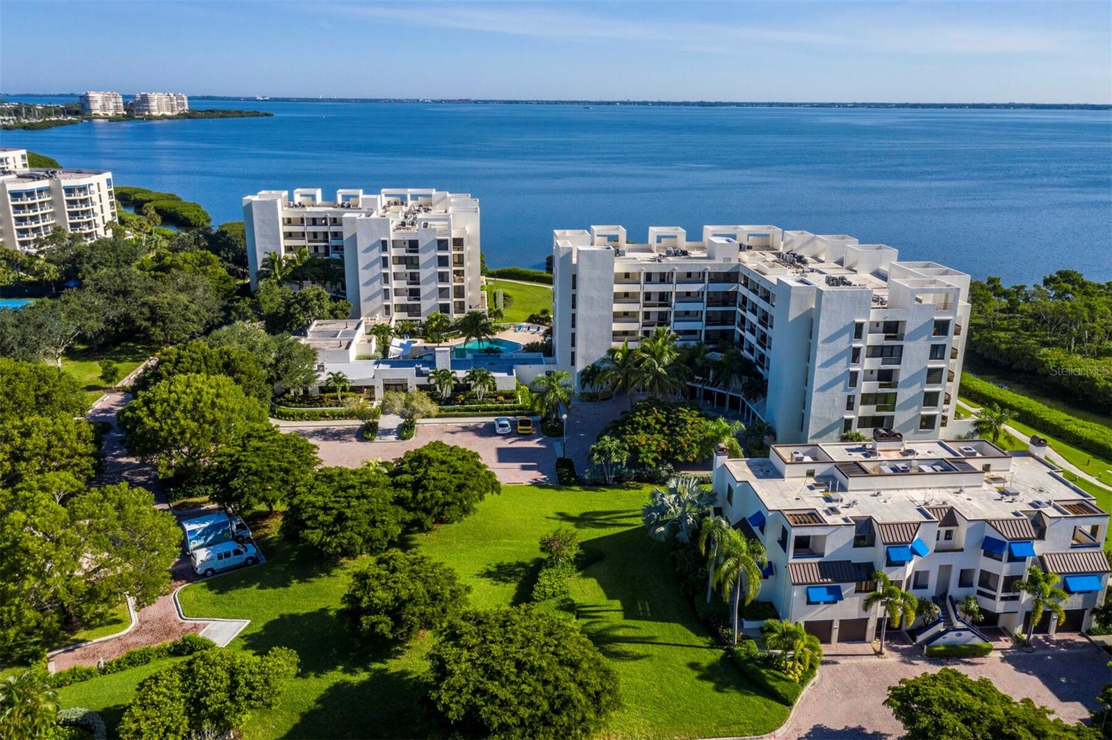 Located on the 5th-floor penthouse level of Fairway Bay, this corner 2BR/2BA residence offers beautiful views of Sarasota Bay, the downtown skyline, manicured grounds, pool, and mangrove channels. Garage parking, a rare and desirable feature on Longboat Key, adds to the appeal. From the moment you enter, a wall of sliders draws your eye through the living room to the bay beyond. Tile floors run through the main living areas, and the open layout includes a spacious living room with a flexible bump-out area ideal for extra seating, a reading nook, or workspace. The dining area flows to the kitchen, which features a functional layout, breakfast bar, and adjoining eat-in area with sliders opening to the side terrace. The primary suite offers bay views, built-ins, a walk-in closet, direct terrace access, and a bath with dual vanities, separate water closet, and excellent potential for updating. The guest bedroom is comfortable and includes an en suite bath. The corner terrace extends the living space outdoors, offering a peaceful setting from morning light on the water to the evening glow of downtown. One of the true highlights of Bay Isles living is deeded private beach access through the Bay Isles Beach Club, a resident-only Gulf-front retreat with an on-site attendant, covered gathering and picnic areas, restrooms, changing rooms, barbecue grills, volleyball court, and beach accessory storage. Fairway Bay residents also enjoy 24-hour gated security, tennis courts, fitness facilities, walking paths, and the benefits of Bay Isles living. Optional Longboat Key Club memberships offer access, depending on category, to championship golf, Har-Tru tennis, private dining, beach and pool club facilities, spa, fitness center, wellness studio, club events, and marina amenities. Deepwater slips may also be available separately.