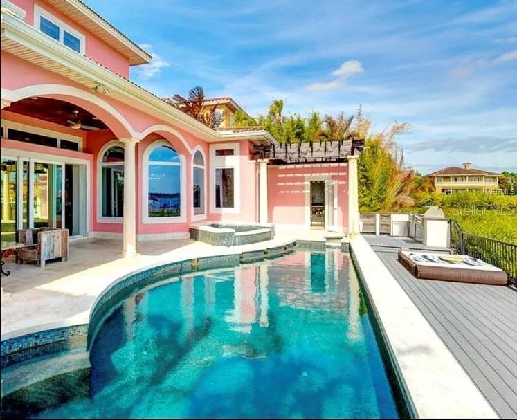 Exquisite tropical waterfront 4-bed, 3-bath, 2-car garage home featuring breathtaking open bay views and top-tier amenities for the most discerning buyer. The expansive open floor plan is designed to showcase stunning water vistas, with floor-to-ceiling glass walls seamlessly connecting indoor and outdoor living. Enjoy mesmerizing sunsets from your private dock with a lift, a chic outdoor entertaining area, and a brand-new heated saltwater pool with a spillover spa. Relax in the infrared sauna with hot/cold plunge pools or gather around the outdoor fireplace on the stunning porch, complete with an outdoor kitchen and panoramic water views. Luxurious finishes include elegant stonework and striking bamboo tray ceilings, creating the ultimate tropical retreat. The chef’s kitchen is equipped with Sub-Zero appliances, stone countertops, a wet bar with a wine cooler, and a butler’s pantry. The expansive second-level master suite features a private waterfront terrace, a designer custom closet, dual sinks, and a jetted spa bath. Located in a gated community with a two-car garage, this home offers the pinnacle of luxury waterfront living.