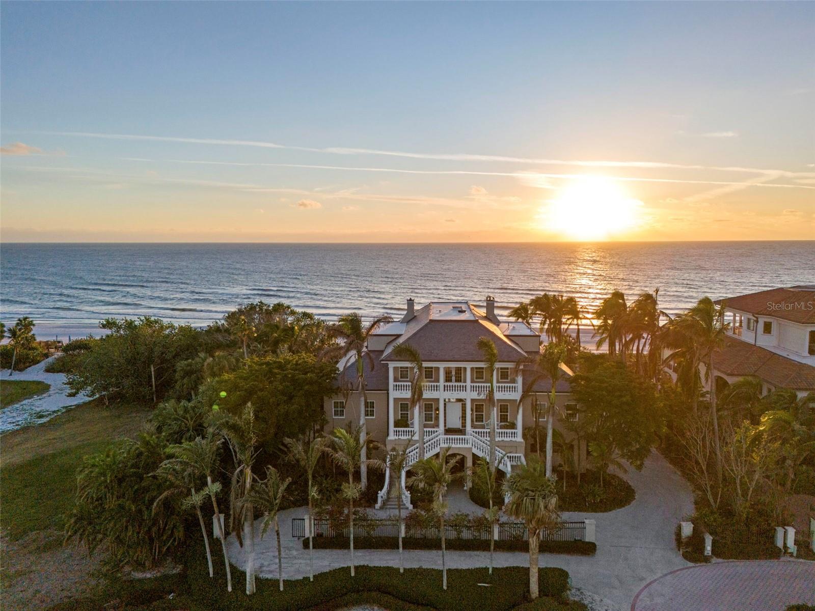 Welcome to a truly remarkable legacy estate spanning 150’ of walking beach tucked behind the gates of the exclusive Longboat Key Club in Regent’s Court. Unquestionably, one of the area’s most distinguished and desirable locations. Perfectly positioned on a quiet street, this custom built residence offers unparalleled views of the Gulf of Mexico, lush tropical landscaping, and is designed for the ultimate Longboat Key lifestyle. Boasting 5-bedrooms, 5.5-bathrooms, the home is a masterpiece of traditional island-style design, featuring soaring ceilings, exquisite trim, and detailed moldings throughout. Expansive verandahs overlooking the Gulf create seamless indoor-outdoor living spaces, perfect for entertaining or simply savoring the tranquil surroundings. Quick access to the beach with a walk-over shared with your neighbor. 
Greet your guests in a formal and elegant gallery, with exceptional views of the Gulf of Mexico. A lovely music room off the gallery is reminiscent of a gentler time when entertaining guests was an artform. The formal dining room complete with exquisite built-in alcoves is perfect for a five-course dinner party with a butler’s kitchen conveniently located for service. The large kitchen with oversized informal dining area features two chandeliers. The island bar provides additional casual seating. A wet bar with sink and wine storage, gas range, microwave, built in oven and Sub-Zero refrigerator make cooking a delight. A large family room with built in shelves is the perfect place to gather with family and friends. A beautiful office with custom wood built-ins, cozy fireplace and plantation shutters provides a quiet spot to work, read or simply enjoy the views of the water. The spacious first floor owner’s suite is a private retreat unto itself, offering two separate bedrooms and bathrooms and spacious custom closets.  Four additional second floor guest suites provide plenty of room for guests or family. An additional family room with fireplace and built in bookshelves opens onto the verandah for viewing sunsets. The resort-style tropical pool and hot tub are framed by a spacious patio, surrounded by lush greenery that ensures privacy and serenity. The walkway to the beach is conveniently located near-by. This home is perfect for the car enthusiast with room for 8 cars in the garage and lots of storage including an elevated enclosed climate-controlled  storage room. For convenience, an elevator provides easy access to all levels of the home. Whether relaxing on the verandahs, hosting gatherings by the pool, or enjoying the serenity of the Gulf, this estate embodies the finest in elegant beach front living. Don’t miss the opportunity to own this prestigious Regent’s Court estate home.