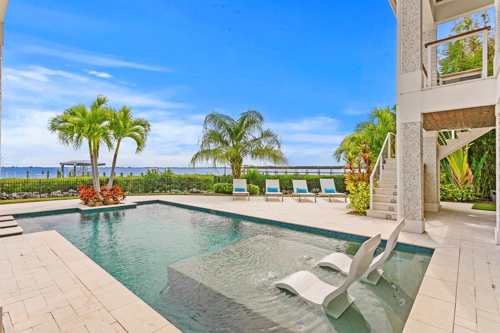 Custom Built British West Indies gated estate on 1.3 Bayfront acres with rarely found garage parking for up to 10 cars and Rooftop Terrace. Welcome to this Private Paradise with a spectacular 9-mile water view and deep-water dock/lift. With no neighbors for ~ 1/2 mile on either side, you will own one of the largest residential waterfront home sites available on Tampa Bay with the WIDEST views! Designed to feel like a tropical resort, this Boss & Mennie Luxury Homebuilders 2019 built quality construction features refined finishes throughout, superior energy efficiency and smart home technology. Built to V Zone building codes with exterior concrete block and pile foundation construction, impact windows/doors, and elevated FEMA-compliant living for flood risk reduction and optimal insurance premiums. Enjoy refined finishes and superior appointments throughout with over 7,125 SF Under Air which includes an oversized garage with parking for up to 10 cars and 3 stop Elevator. You’re welcomed by a dramatic two-story foyer and great room, grand staircase and impressive ceiling detail featuring up to 6 bedrooms and 6.5 baths. Expansive living spaces include a formal living room with wet bar, formal dining room, two master suites, office (opt 6th bedroom) and large bonus room. Enjoy an open kitchen offering top-of-the-line appliances and butler’s pantry, custom cabinets and quartz counter tops. Escape outdoors to expansive terraces, heated pool/spa with sun shelf and bar stools, outdoor kitchen, and spectacular rooftop terrace. Additional appointments include impact rated windows and doors, natural gas tankless water heaters, elevator, solid block construction, home generator, power shades, gated entry.  The quaint community of Safety Harbor, home to Safety Harbor Resort and Spa, offers distinctive shops, award-winning restaurants, galleries and downtown center. Nearby Philippe Park boasts a boat launch, fishing, picnic, playground and rock-climbing park. Centrally located in the Tampa Bay area offering easy access to both airports, beaches and downtown Tampa/St. Petersburg.