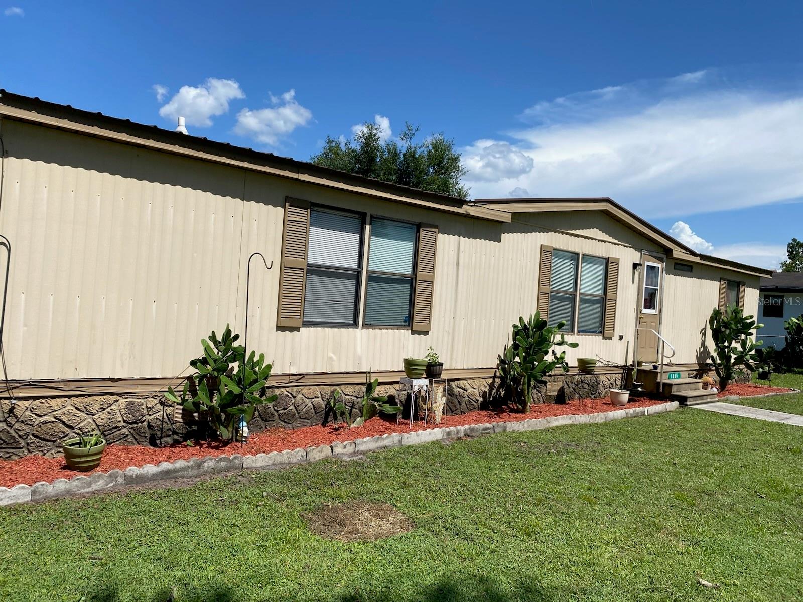Beautiful 4-Bedroom 2 Bath, Manufactured Home in Kanuga Village – St. Cloud, Florida.  Welcome to this well-maintained 4-bedroom, 2-bathroom home located in the desirable Kanuga Village community. This spacious home features an extended kitchen with granite countertops, a large granite island, updated cabinetry, and ample workspace, making it ideal for cooking and entertaining.  The open-concept floor plan seamlessly connects the living room, dinette, and kitchen areas, creating a bright and inviting space for family gatherings and everyday living. Laminate and tile flooring throughout provide durability and easy maintenance.The primary suite includes an ensuite bathroom with a shower and granite single-sink vanity. The second bathroom also features a shower for added convenience.  Additional features include a water softener system, undersink filtration system providing enhanced water quality throughout the home.  Situated on a corner lot, the property offers exceptional outdoor amenities, including an RV carport, a storage shed with a second-story loft area, a steel roller garage door, and a side-entry door connected to the RV carport. Enjoy Florida living year-round from the covered and screened carport area, perfect for relaxing or entertaining guests.  This property combines functionality, storage, and outdoor space in a convenient St. Cloud location. Schedule your showing today! ***HOA Fees, home square footage, and taxes, lot sizes and schools; MH width and straps under manufactured home and are to be independently verified.***
