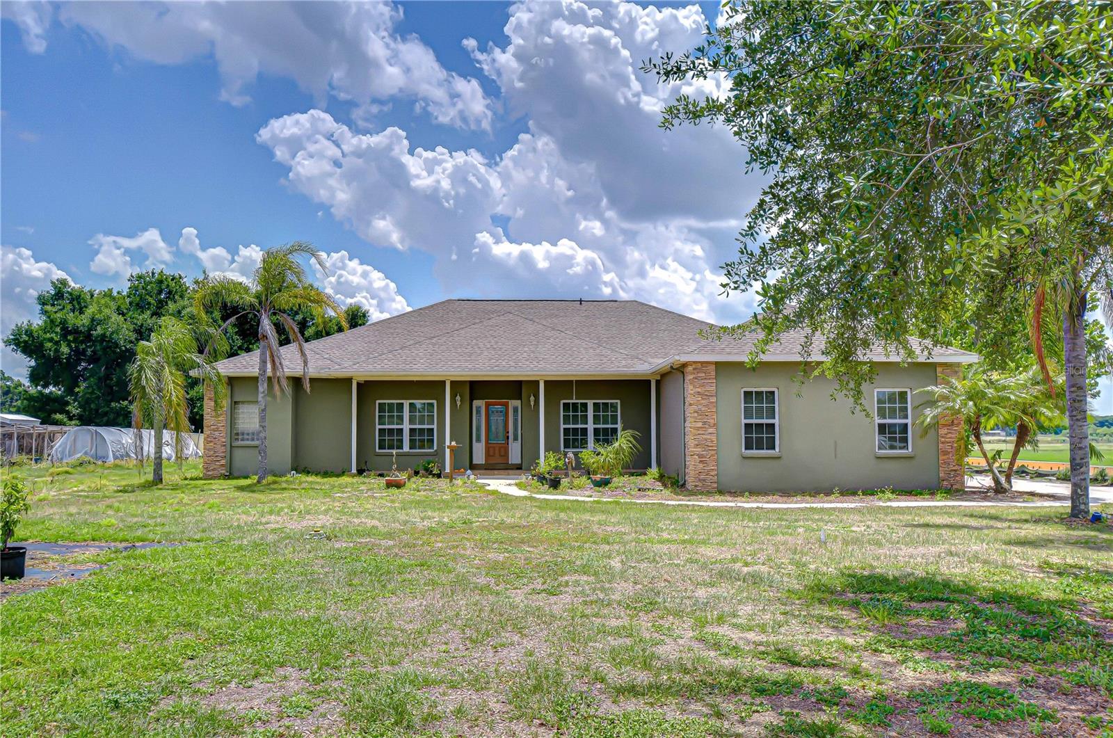 Escape to the space and serenity of country living with this beautifully cared-for 4-bedroom, 2-bath home set on over an acre of land. Offering both privacy and functionality, this property is ideal for those who want room to spread out without sacrificing comfort. From the moment you arrive, the expansive front yard—enclosed with vinyl fencing—and charming tiled front porch create a welcoming first impression. It’s the perfect spot to unwind and take in the peaceful surroundings. Inside, the home features a thoughtfully designed layout with a formal dining space at the front, showcasing scenic views of the property. The main living area is warm and inviting, highlighted by a tray ceiling, wood flooring, and sliding glass doors that open to the lanai for effortless indoor-outdoor living. The kitchen is both stylish and practical, offering abundant cabinetry, ample counter space, a center island, and a spacious pantry. Stainless steel appliances are included—featuring a brand-new stove—along with the washer and dryer for added convenience. Just off the kitchen, a bright dining nook is framed by a large picture window and French doors leading outside. A split-bedroom layout provides added privacy, with the primary suite tucked away and featuring direct lanai access, a generous walk-in closet, and an ensuite bath complete with a jetted tub and separate walk-in shower. Three additional bedrooms are located on the opposite side of the home, including a flexible fourth bedroom currently used as an office. All bedrooms include ceiling fans, and one guest room features a double closet. The secondary bathroom offers built-in storage and direct access to the lanai—ideal if you envision adding a pool in the future. A dedicated indoor laundry room includes a utility sink and extra storage space. Step outside to the covered lanai with tiled flooring and ceiling fan, overlooking a wide-open backyard ready for entertaining, pets, or recreational use. A dog run is already in place and can be removed if desired. Additional highlights include a newer roof (2022), water heater (2023), exterior paint (2022), and freshly painted garage (2023), along with a flagpole that will remain with the home. With ample space for animals, outdoor toys, and gatherings, this property delivers the freedom and lifestyle that country living is all about.
