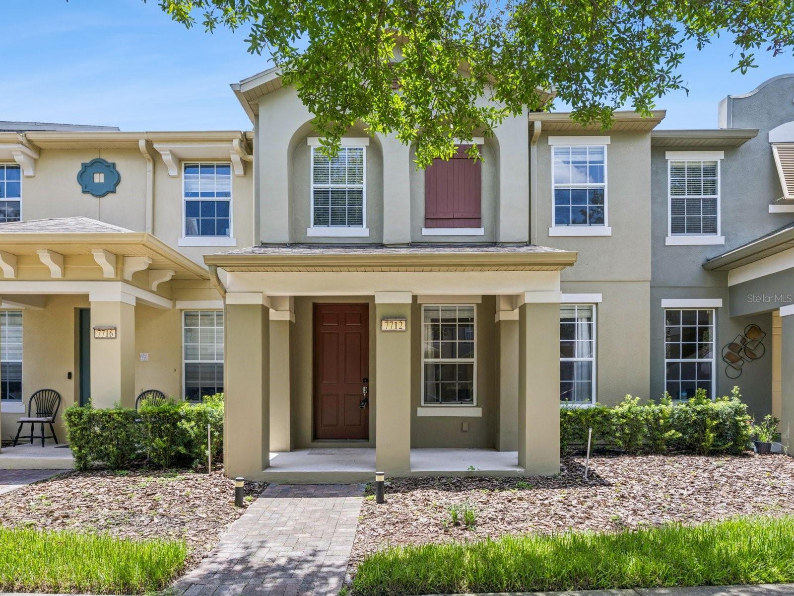 This Berkshire Place townhome offers a thoughtfully arranged two-story layout with three bedrooms, inviting living spaces, and a convenient Windermere location. The covered front porch opens to a bright living room with a ceiling fan, while the adjoining dining area creates an easy connection to the kitchen. Dark wood cabinetry, stainless-steel appliances, recessed lighting, a window above the sink, and a raised breakfast bar provide a functional kitchen setup with space for casual seating. A half bathroom completes the main level. Upstairs, the primary suite features windows on two sides, a walk-in closet, and an en suite bathroom with a long dual-sink vanity and enclosed shower. Two additional bedrooms, each with a ceiling fan and closet, share a full bathroom with a tub and shower combination. Just beyond the dining area, double glass doors open to an enclosed brick-paver courtyard that provides a low-maintenance setting for outdoor dining, grilling, or container gardening. The courtyard also connects directly to the rear-entry two-car garage, creating convenient access between the home and parking area. Berkshire Place offers tree-lined sidewalks, a playground, a community pool overlooking the water, and sports courts, adding opportunities to enjoy the outdoors close to home. Located in Windermere’s Lakeside Village area, the townhome is convenient to nearby grocery stores, shopping, restaurants, and everyday services, with access to Winter Garden Village, area theme parks, and destinations throughout Central Florida.