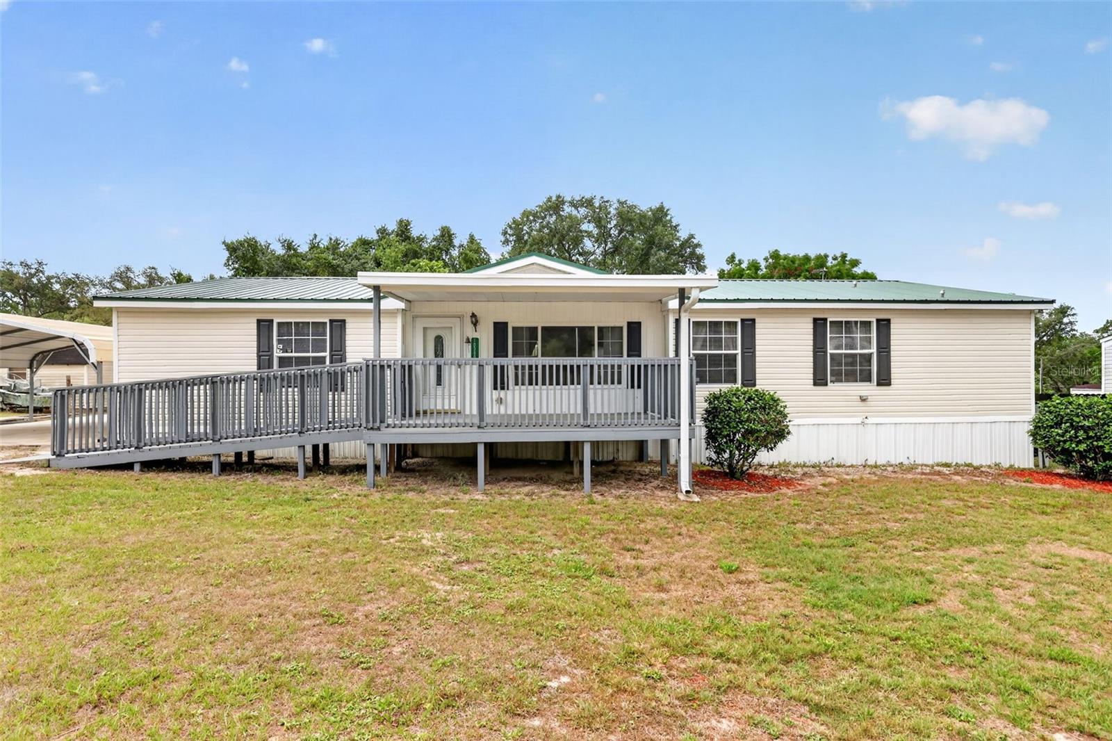 Looking for an affordable place to call Home with NO HOA , Lot Rent, or Water & Sewer Bill?  Then this 3/2, almost, 1800 Sq Ft  Modular home on your private lot with Well and Septic is a must see option. This immaculate Home offers
a large 11X16 Front Covered Porch with soft approach incline ramp allowing for easy wheelchair accessibility.  Open
the front door and enter a large Open Concept floor plan featuring Vaulted ceilings throughout. The first room can be
utilized as a Formal Living Room, Work Space, or Game room, large enough for that Pool Table! This area features
Laminate flooring that also leads in to your spacious Dining Area, Family Room with built In TV and Book Shelves as
well as a generous sized Kitchen with plenty of Cabinets with that must have double kitchen sink.  Here you'll find Oak
Cabinets and white Appliances plus plenty of natural light.  Needing more light to cook, flip a switch for your overhead
ceiling spot lights!  Continue through the Kitchen into your separate Laundry Room with Washer and Dryer. This area
also offers a rear back door Exit opening onto your 10X16 Deck overlooking the Fenced Back Yard. Perfect for Pets!
The other side of the Laundry room opens into a full Guest Bath Room with large Vanity, as well as a walk in Shower.
Convenient to both access from the rear deck and Hall Entry from your two Guest Bedrooms. The Primary Bed Room
En-Suite has those Vaulted Ceilings, Large Walk In Closet, plus, a Spa Inspired Bath complete with a Corner Garden
Soaking Tub, Double Sink Vanity, Stand alone Shower and a matching Linen Cabinet. No Space wasted in this Home.
At the end of the Bedroom Hall you'll find a Built in Desk Area offering wall Cabinets, as well as, multiple desk drawers 
and side desk cabinet. Just enough space tucked away for your Home Office. Did I mention, all three Bedrooms have
walk in closets, so much storage space! The Bonuses continue outside where you'll have covered parking for two cars
under your large Carport with Cement Foundation. The drive way also has room for additional parking as well. Beyond
the Carport is a large CLEAN Workshop complete with workbench and, an additional Storage building that houses the
Well Pump keeping it out of direct sunlight. This building is perfect for lawn equipment, bikes, or just additional storage
items. Both these buildings open to the rear yard as well. This well kept Home offers an appealing peaked Metal Roof,
giving you years of peace of mind. Come take a look at all this property has to offer. The possibilities are endless.