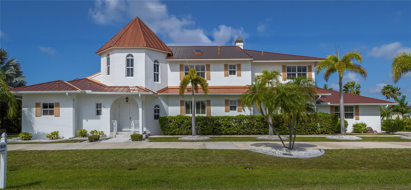 This stunning Mediterranean-style executive estate sits on two premium waterfront lots offering 160 feet of sailboat-access canal frontage — the ultimate setting for the serious boater or coastal lifestyle enthusiast. Located in the sought-after Punta Gorda Isles community, this one-of-a-kind home delivers the perfect blend of Old World elegance and modern Florida waterfront living. Enter through an impressive tower entrance that sets the tone for everything that follows. A beautifully crafted solid oak staircase greets you upon arrival. The heart of the home is a soaring great room with its dramatic ceiling height, walls of windows flooding the space with natural light, and rich oak paneling adding warmth and sophistication. The main sitting area anchors around a classic fireplace — ideal for Florida's cooler evenings — while the open layout accommodates multiple conversation areas perfect for entertaining on any scale. Gleaming 24-inch tile flows throughout the living areas on the main floor, and a wraparound second-floor balcony overlooks the entire space from above. The well-appointed kitchen features 42-inch cabinetry, Corian countertops, stainless steel double refrigerator/freezer, a center island with cook top, built-in desk, and casual dining area. Every inch has been designed for the home chef who loves to entertain. The adjacent formal dining room is bathed in natural light, framed by handsome wood beam ceilings, and overlooks the pool and waterfront. Built-in corner cabinetry throughout provides generous storage without sacrificing style. The expansive master suite is a private sanctuary. A newly installed private elevator connects the master level directly to the upstairs den, adding a sophisticated convenience rarely found in residential properties. The recently updated master bath showcases white wood cabinetry, dual sinks, a deep soaking tub, and a generous walk-in shower. A large walk-in closet and a separate walk-in linen closet ensure that storage is never a concern. An adjoining air-conditioned flex room — ideal as a home gym, workshop, or creative studio — includes a half bath. A second bedroom on the main floor near the entry features a custom built-in bed and walk-in closet, served by a beautifully updated bath with wood cabinetry, marble countertops, and a walk-in shower. Upstairs, a third bedroom offers access to a large cedar-lined closet as well as  a full bath featuring a tub, tile floors, and quartz countertops. At the end of the upper hallway, a handsome oak-paneled den with fireplace provides a quiet retreat. Rounding out the upper level is a delightful English-style pub complete with built-in bar seating and custom woodwork — great for entertaining and a truly unique feature that sets this property apart from anything else in the area. The screened lanai features a sparkling pool and spa alongside a gallery-style covered passage along the exterior of the great room — an elegant transition between indoors and the waterfront. The double-lot configuration and generous seawall provide ample space to dock the boat of your choice with direct sailboat access to Charlotte Harbor and the Gulf of Mexico beyond. Whether you're a day sailor, offshore angler, or simply love waking up to waterfront views, this property delivers the quintessential Florida boating lifestyle. See this property today! You won't be disappointed!