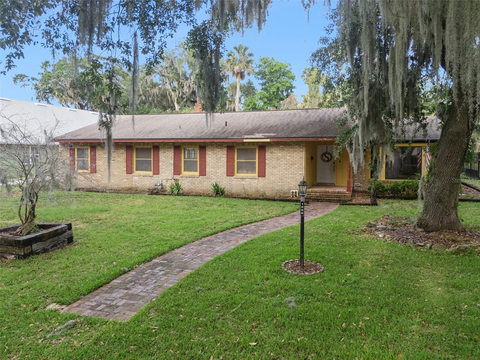 Welcome home to this spacious and versatile 5-bedroom, 3-bath home with over 3,000 sq. ft. and NO HOA in the heart of Leesburg! Featuring a private interior in-law suite complete with its own kitchenette, this flexible layout is ideal for multi-generational living or extended guests. Tucked away for a sense of privacy, you're still just minutes from shopping, dining, downtown Leesburg, Venetian Gardens, the community boat ramp to the Harris Chain of Lakes, ski beach, and endless local events and entertainment. The heart of the home showcases a beautifully updated main kitchen featuring high-level granite countertops, stainless steel appliances, rustic knotty pine cabinets, and updated tile flooring. Multiple spacious living areas provide room for everyone, while both a brick fireplace and a cast iron fireplace create the perfect setting for cozy evenings at home. Step outside and enjoy Florida living at its finest on the screened-in paver patio, perfect for year-round relaxing or entertaining. The fully fenced backyard includes a raised garden, a convenient outdoor sink, and separate golf cart parking. Whether enjoying peaceful mornings outdoors, hosting family gatherings, or enjoying boating, fishing, skiing, and more, this property offers a lifestyle as inviting as the home itself, just minutes from your front door. This is more than just a home—it’s the complete Florida lifestyle package! *Aerial photo property lines are an estimate and to be verified by buyer.