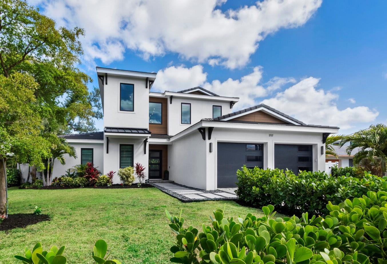 Prime Location in the Hudson Bayou neighborhood. Built in 2023 this home offers 5 Bedrooms, 4.5 bathrooms and designer finishes. The interior features an open floor plan with wide plank wood flooring throughout and impact-rated windows and doors. The great room is anchored by a tray ceiling, custom built-ins, and a marble fireplace feature wall. The kitchen is designed for both everyday living and entertaining, offering Viking appliances, a dual fuel range, built-in refrigerator, custom cabinetry, quartz countertops, and a walk-in pantry. A dedicated wine room is located just off the kitchen. The primary suite is positioned on the first floor with direct access to the lanai, two custom walk-in closets, and a well-appointed bathroom with dual vanities, soaking tub, and frameless glass shower. The main level also includes a flexible office or guest suite with a full bath, along with a spacious laundry room. Outdoor living is fully integrated with a covered lanai featuring a complete outdoor kitchen with gas grill, vent hood, sink, and refrigerator, along with electric screens. The heated saltwater pool and spa are finished in PebbleTec and complemented by a gas fire feature, updated landscaping for privacy, and an outdoor shower. Upstairs includes three additional bedrooms, all with walk-in closets, two full bathrooms, and a loft space. Additional features include Sonos audio on the main level and  natural gas generator. Located within the Southside Elementary school district, with a neighborhood park nearby. Downtown Sarasota, the Bayfront, Marie Selby Botanical Gardens, and Southside Village are all just minutes away, with convenient access to the Lido Key and Siesta beaches.