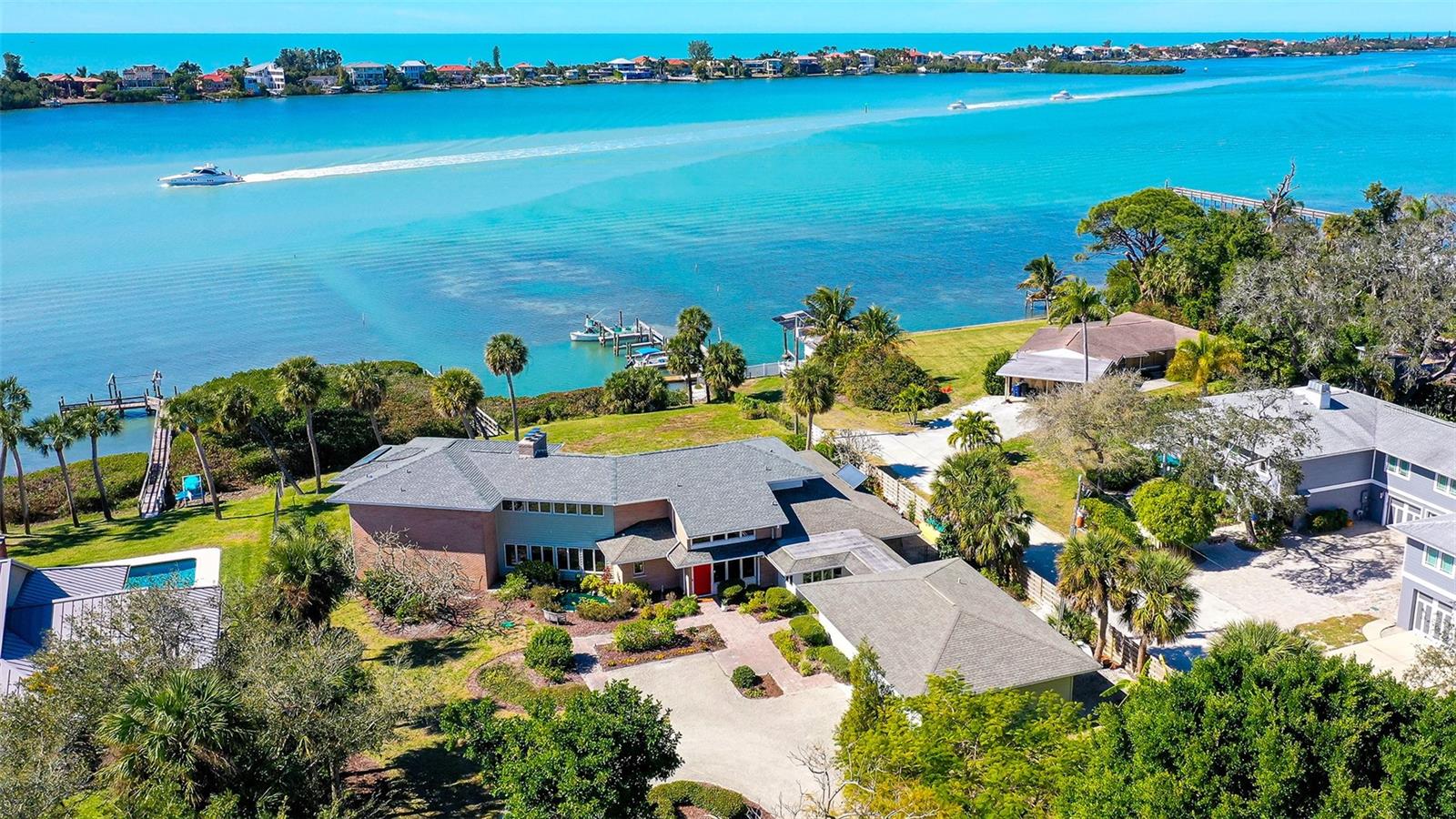 One or more photo(s) has been virtually staged. This custom-built, one-owner, four-bedroom, 4,600 square foot home is located above the base flood elevation on a wide one-acre parcel, offering privacy, space, and over 130 linear feet of private water frontage on a wide stretch of the intracoastal waterway. A huge bonus: it is not in a flood zone and sits at 13 ft elevation. There was zero flood/surge damage from Helene or Milton. The home has wonderful curb appeal and is set back from the street with a circular driveway and a brick pathway flanked by a well-stocked koi pond. You enter the two-story foyer which opens up onto a large, light filled living room with soaring 19 ft ceilings, rich wood floors, a wood-burning fireplace with floor to ceiling coral stone surround, and sliders out to the sun-soaked pool deck. There is a formal dining room, a separate family room with wet bar and ice maker, a large kitchen with an adjacent breakfast room, a butler's pantry and an antechamber that is set up to be a wine storage room. The kitchen has a double oven, huge Subzero freezer, separate refrigerator and plenty of countertop space, and a handy passthrough to the family room. There are two bedrooms on the first floor and a bathroom which serves as a pool bath if you don’t want to rinse off in the outdoor shower. In addition to the four bedrooms and office in the main house, there are two additional air-conditioned work/hobby spaces in the garage, which is accessed via a covered walkway. One of the rooms faces north and was used as an art room. The other is sound-proofed and could work well as an office, dark room or gym. The oversized garage has a workbench. The second floor has two sections connected via a walkway overlooking the main living area. To the right is a nice sized bedroom and ensuite bathroom and to the left is the primary suite with a beautiful wood-paneled office with rich wooded cabinetry and a wood burning fireplace. A screened balcony off the bedroom and office offers unparalleled views of the intracoastal waterway and some of the Gulf coast’s finest sunset skies. These wide-open west-facing views are part of what makes this home an incredible opportunity for its new owner. There is a covered screened lanai as well as uncovered outdoor living and dining space. The pool is huge and has a max depth of 8 ft.  Enjoy a navigable route out to the main channel. Take this incredible .97-acre waterfront property, make it your own, and enjoy endless sunsets and all that the Florida lifestyle has to offer!