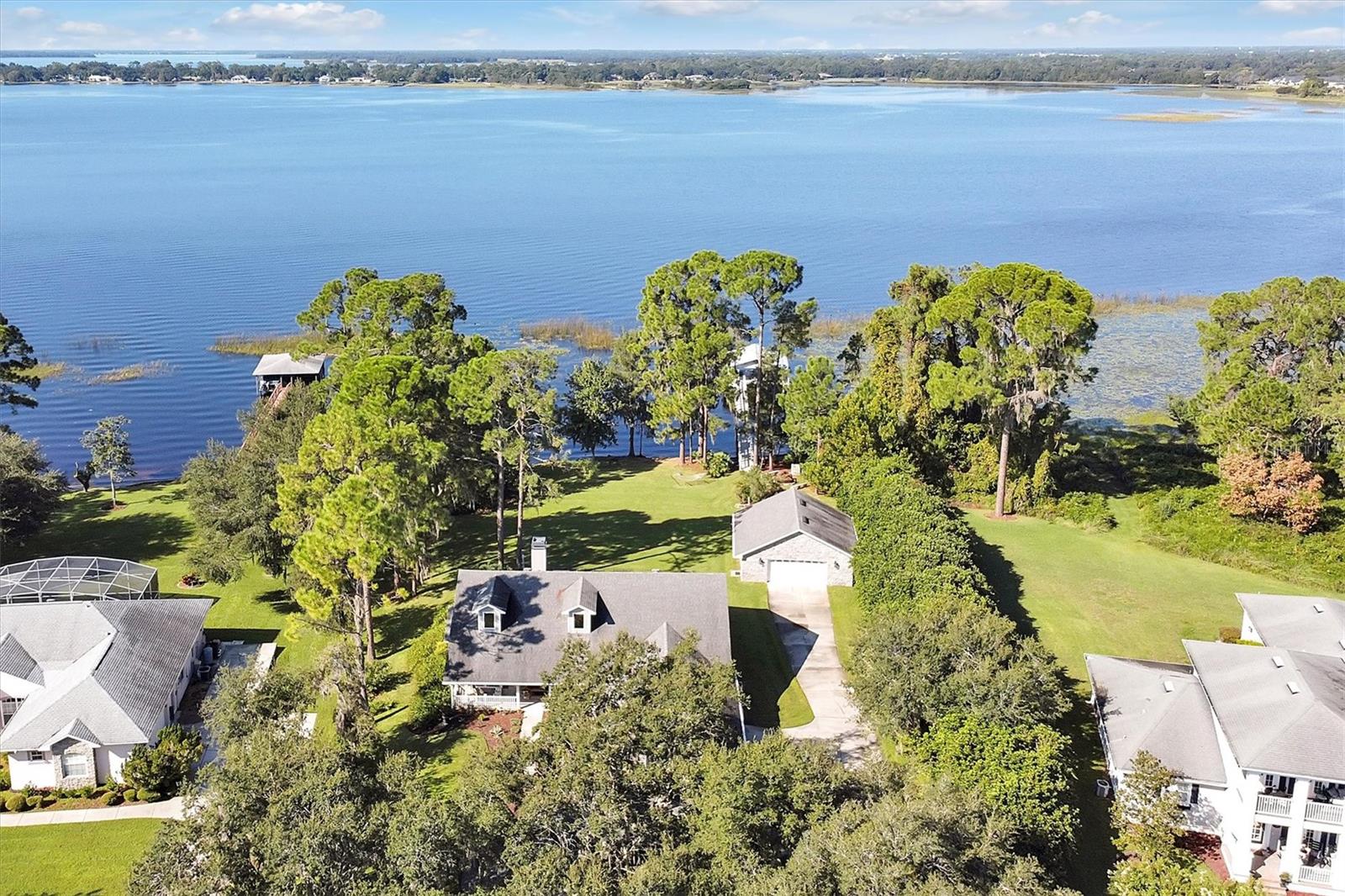 PRICE ADJUSTMENT BELOW APPRAISAL VALUE, LAKEFRONT LIVING ON THE CHAIN OF LAKES: This picturesque lakefront home is located in the highly desired community of NorthShore on Lake Lizzie and offers over 150’ of pristine lake frontage. Just step out, launch your kayaks and go for a paddle around the lake. Located on one acre complete with 125’ dock with boathouse, boat lift and a jet ski floating dock. Plenty of room for your outdoor furniture to entertain, watch the sunsets and fishing. Dock has water hookup, electrical supply, outdoor lighting and dimmable ambient lighting.
Your lake home features over 2,300 sq. ft. of living area. Open floor plan is great for entertaining family. When guests arrive they can utilize the gravel circle drive, enjoy the gorgeous view of the front yard with lush landscaping, beautiful Staghorns, and an outstanding view of the lake. Upon entering the home you will be stunned by the large stone wood-burning fireplace, 12’ sliding glass doors leading out to the covered lanai offering a great view of the lake complete with remote-controlled blinds. Vaulted ceilings with dormer windows offer plenty of natural light in the home for that warm, inviting feel. Upgrades to the home in the past few years include new luxury vinyl plank flooring, 5” baseboards, light fixtures, ceiling fans, New South high quality windows (picture windows along entire lake side of home), new owner’s bathroom with dual head walk-in shower and closet with custom built organizational system, solid core doors, new hardware, new water softener system, interior/exterior paint, low maintenance landscaping and gutter system. Kitchen includes granite countertops, soft close cabinets, pull-out cabinet shelving, cooking island, beverage area and breakfast bar. Did I mention over 1500 sq. ft. of garage space? Attached garage is over 650 sq. ft. – plenty of parking for your larger vehicles plus still plenty of storage and ladder access for storage above. The detached garage/workshop is 900 sq. ft. also with storage above and 220V hookup for your welder, etc. Enjoy building a fire in the fire pit located next to the lake, enjoy your favorite hot beverage and roasting marshmallows.
Exploring the chain of lakes includes six lakes to enjoy water recreation and nature at its best. Cypress, pine and oak tree shorelines, fishing and bird watching. Don’t forget the fun of skiing, wake boarding and swimming, pull up the boat at a favorite locals sandbar, or just enjoy a relaxing boat ride. Don’t settle for that small pond: Alligator Lake, 3,406 acres; Lake Lizzie, 792 acres; Brick Lake, 616 acres; Center Lake, 410 acres; Trout Lake, 273 acres and Coon Lake, 148 acres. And just a few minutes away is the Lake Lizzie Nature Preserve where you will enjoy hiking, biking, & horseback riding. Or just pull up your boat, kayaks or paddleboards and enjoy lunch at the public picnic area. Cruise thru the canals between the lakes and enjoy a large variety of birds and all type of wildlife making for a relaxing day on the water. 
The community of NorthShore offers a private boat ramp, walking trail and dock for all members of the community. Sellers are offering up to a $500 one year home warranty provided to buyers. Conveniently located within minutes to Lake Nona, Medical City, Orlando Airport, and just minutes to the beaches. Don’t miss this great opportunity, schedule your showing today…