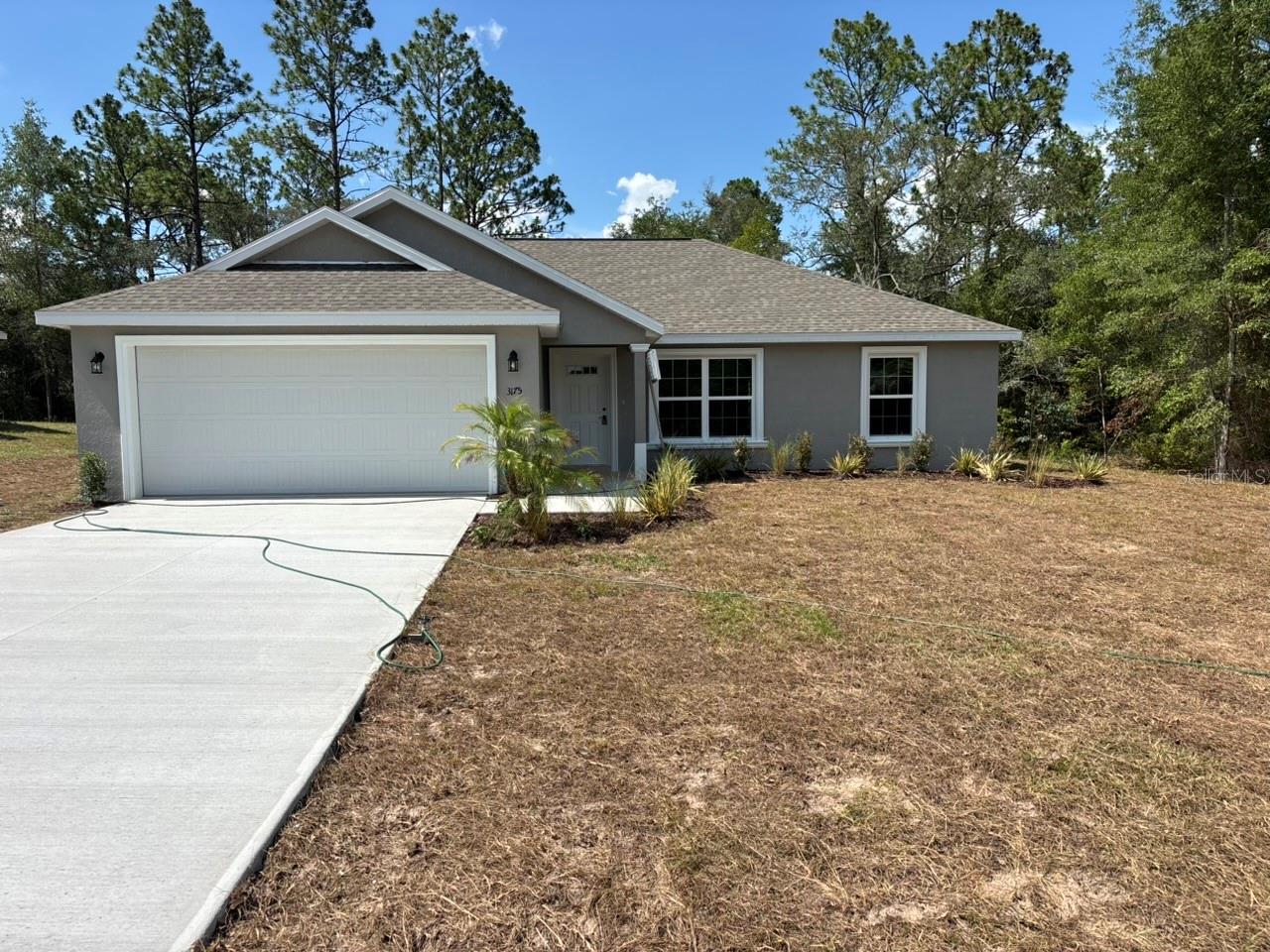 NEW CONSTRUCTION. MOVE-IN READY! The Key West Model in Citrus Springs offers 3 bedrooms, 2 bathrooms, and 1,405 square feet of comfortable living space. Built for lasting value, this home features concrete block construction, a 30-year architectural shingle roof, energy-efficient double-pane windows, and a 10-year structural warranty. Inside, the open, split-bedroom floor plan features vaulted ceilings and luxury vinyl plank flooring throughout. The kitchen includes stainless steel appliances, custom white shaker cabinets with soft-close drawers, granite countertops, and a pantry. Both bathrooms also feature granite countertops for a clean, coordinated finish. Additional features include washer and dryer hookups, a covered patio, sliding glass doors, and an attached 2-car garage with an opener and remotes. Enjoy ownership freedom with no HOA fees, plus a high-and-dry location in Flood Zone X, where flood insurance is not required.