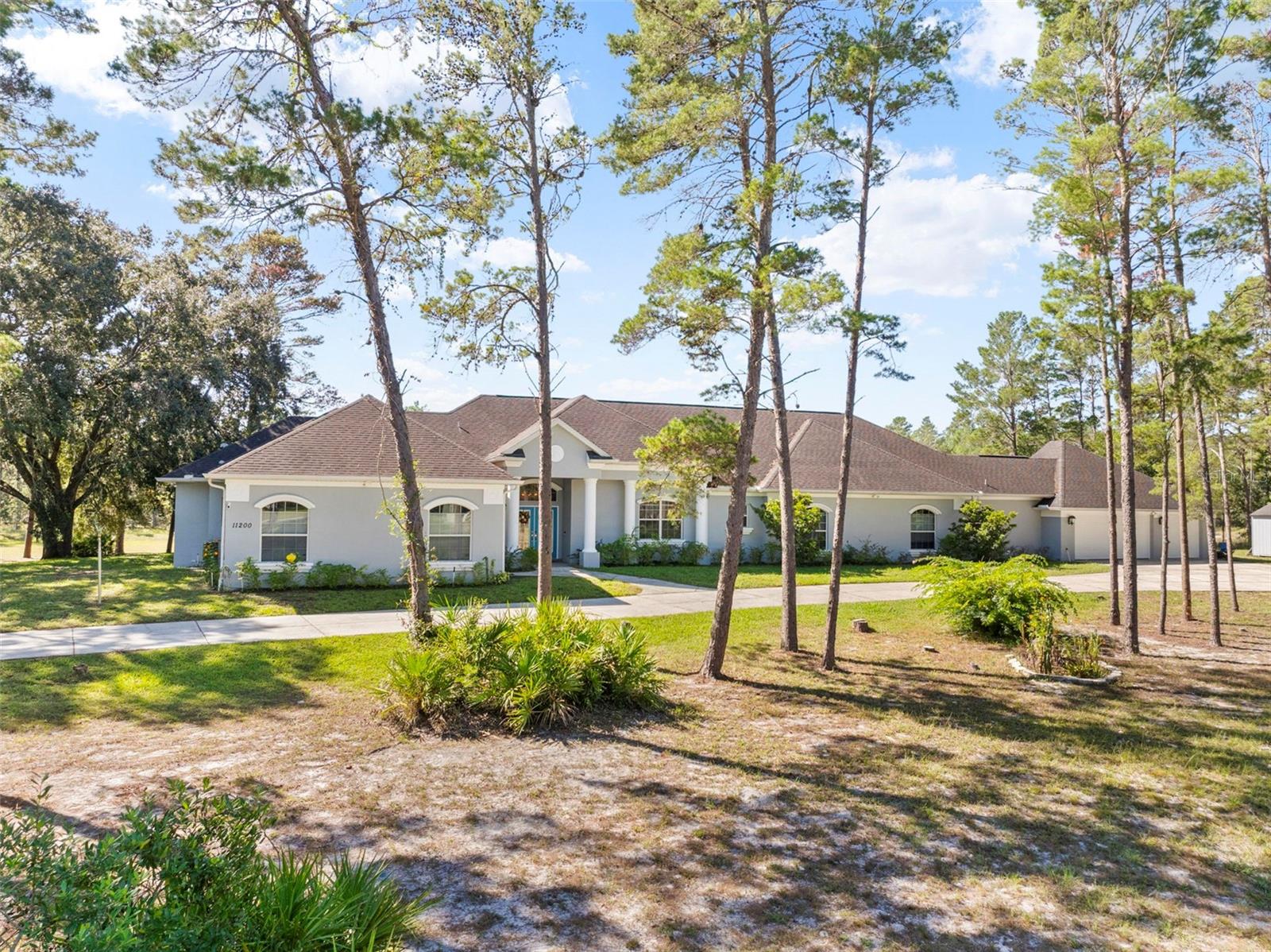MOTIVATED SELLER ~ PRICED REDUCED! This magnificent estate offers a rare opportunity to own a home with 4,409 square feet of living space on more than 4 acres, complemented by the low HOA fees of the sought-after Woodland Waters community. With 6 bedrooms, 3.5 baths, and a 3-car garage (one air-conditioned), the residence provides a sprawling, flexible floor plan that includes a large great room and an additional family room for entertaining. The gourmet island kitchen is a culinary enthusiast's dream, featuring a bar sink, a breakfast bar, and quality stainless steel appliances like dual wall ovens, while large windows in the dining area offer serene, full-glass views of the expansive property. Modern and energy-efficient systems are in place, with two newer A/C units (2022 and 2020) and two water heaters. The outdoor living space is equally impressive, with a huge, screened-in, solar-heated pool with a newer Diamond Brite finish, a 4-person hot tub on the screened back porch, and a chain-link fenced area ideal for pets or children to play. Home is on Hernando County Water but sprinkler system is on an Irrigation Well. A long, double-wide driveway provides abundant parking for an RV or large trailers, and the property is conveniently located just a few miles from the Weeki Wachee Mermaid Attraction, beautiful beaches, and a wide array of shopping, dining, and medical facilities.