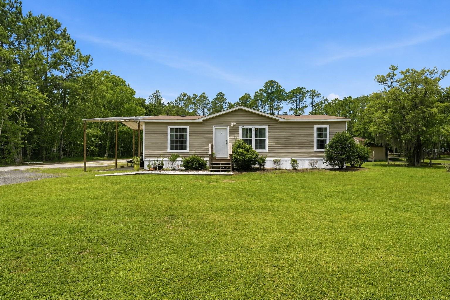 Country living meets modern comfort on 2.27 acres in Bunnell! Built in 2020, this well-maintained 3-bedroom, 2-bath manufactured home offers the space, flexibility, and lifestyle buyers are searching for. Inside, you'll find durable vinyl flooring, a spacious kitchen with decorative molding details and a large pantry, a convenient interior laundry area, and an inviting open layout designed for everyday living. The primary suite features a double vanity and a walk-in shower with a relaxing rain shower head, creating a private retreat at the end of the day. Step outside and discover what makes this property truly special. Approximately one acre is fenced and ready for horses or larger animals, while the remaining acreage provides plenty of room to roam, garden, play, or expand. Homesteaders and animal lovers will appreciate the existing chicken coop, small animal pens, storage shed, and outbuilding/workshop space already in place. Multiple covered parking areas include a large carport that can easily double as a shaded outdoor entertaining space, plus additional covered parking for vehicles, boats, trailers, equipment, or recreational toys. A recently updated septic system adds peace of mind and value for the next owner. Surrounded by mature trees and open grassy areas, this property offers the freedom of country living while remaining conveniently located near Palm Coast, Flagler Beach, Daytona Beach, shopping, dining, and major roadways. Bring your horses, chickens, RV, boat, and dreams, this move-in-ready Flagler County acreage property is ready for its next owner.