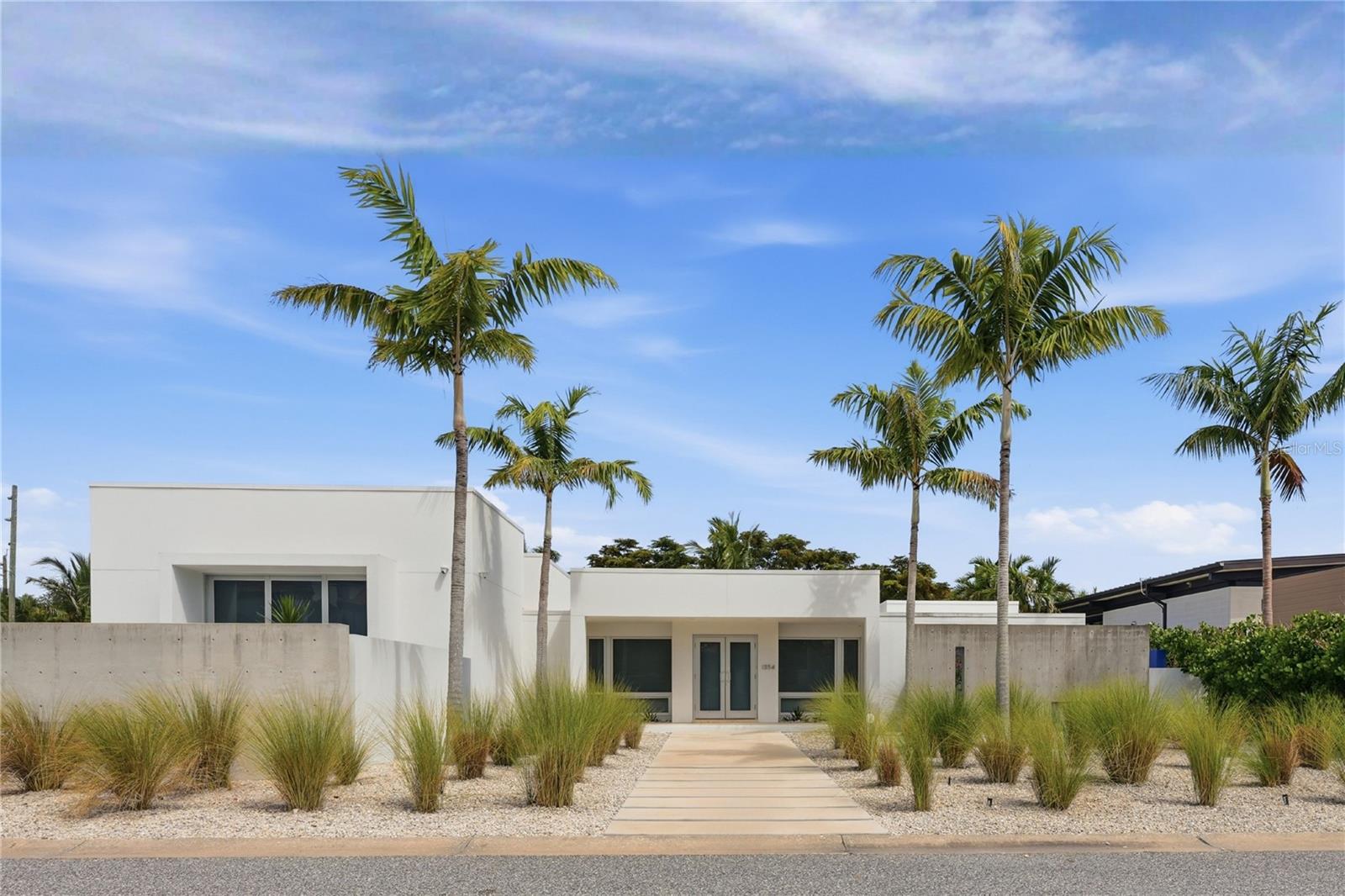 In the coveted enclave of Lido Shores, a community celebrated for its architectural innovation, this striking modern residence stands as a true work of art by renowned architect Guy Peterson. A symphony of clean lines, open volumes, and coastal serenity, the home captures the very essence of Sarasota’s modernist heritage while embodying an effortless sense of luxury and calm. Walls of glass dissolve boundaries between interior and exterior, flooding every space with natural light and blurring the line between home and horizon. In 2022, a thoughtful transformation elevated both form and function, introducing a new dining area, a versatile family room that doubles as a library, enhanced storage, and a dedicated laundry space, all executed with Peterson’s signature restraint and precision. Outdoors, the living experience unfolds across three distinct retreats, each its own expression of tranquility. A Japanese-inspired front courtyard with a water feature welcomes guests with meditative grace. At the center, a lap pool and heated spa anchor the heart of the home, surrounded by lush gardens, a Wolf outdoor grill, and generous lounge areas ideal for entertaining. A third, private garden extends from the primary suite, offering an intimate sanctuary designed for reflection and repose. Inside, refined simplicity defines every space. The open-concept plan seamlessly connects the main living area, dining room, and gourmet kitchen, outfitted with Wolf and Sub-Zero appliances, custom maple cabinetry, and white quartz surfaces that echo the home’s modern aesthetic. The primary suite, with direct access to its secluded courtyard, features a bespoke closet system and serene ambiance that completes this private retreat. Set within a community offering exclusive access to a private Gulf-front beach, this residence transcends the notion of home. It is an architectural statement, an emblem of modern Sarasota design and a rare opportunity to own a piece of its enduring legacy.