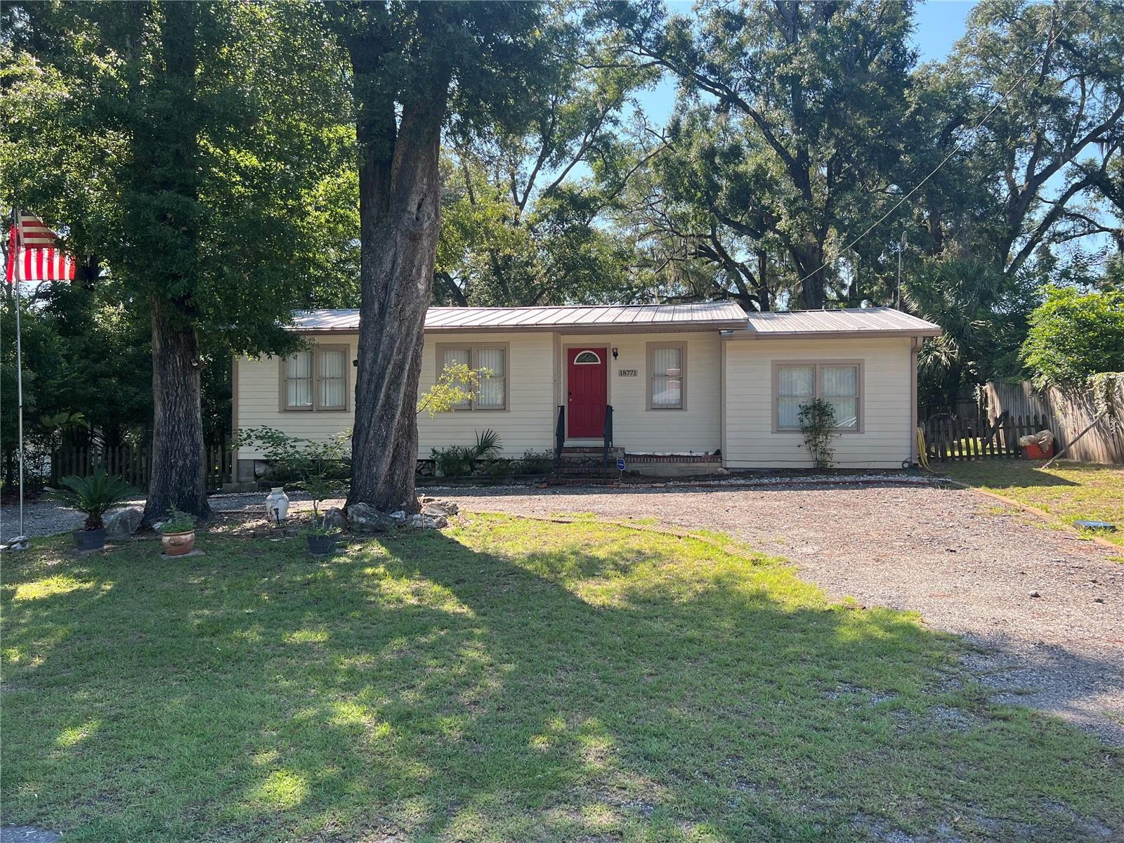 Small-town charm meets everyday convenience in the heart of High Springs. This welcoming community offers a vibrant downtown filled with unique shops, local dining, and popular breweries, all just minutes from easy access to I-75. Enjoy the natural beauty of nearby rivers and springs, perfect for year-round outdoor recreation. This well-maintained home features 3 bedrooms and 1 bath, with a comfortable living and dining room combination ideal for relaxing or entertaining. The kitchen includes a convenient breakfast bar and a laundry closet for added functionality. Laminate flooring runs through the main living areas, while two bedrooms showcase classic hardwood floors. Warm wood paneling in the living space adds character and charm. Situated on a .24-acre lot, the property includes a fenced backyard, a storage building, and a circular front driveway for easy access and additional parking. Durable HardiPlank siding and a metal roof provide long-lasting, low-maintenance living.
