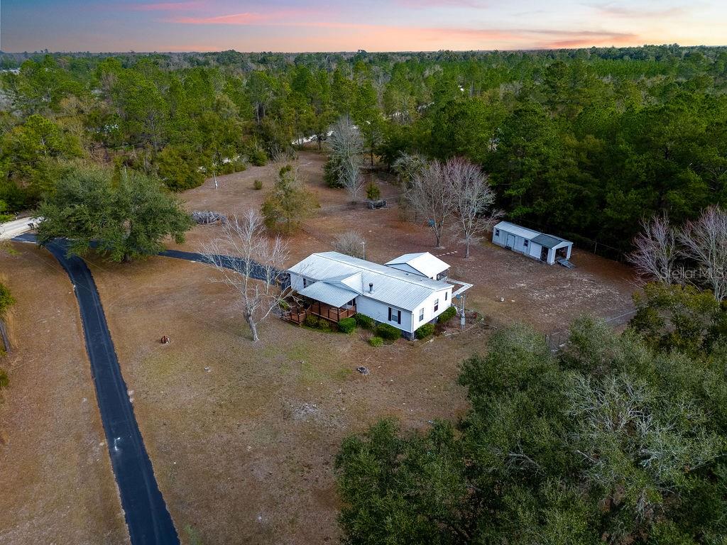 Welcome to this spacious 3 bedroom, 2 bathroom double wide mobile home located at 2774 140th Terrace, Lake City, Florida, just inside  Suwannee County. Sitting on 2.54 cleared acres, this property offers plenty of space, privacy, and flexibility for everyday living while still being close to town. Inside the home, you’ll find a split bedroom layout that provides privacy and comfort. The large master bedroom is located on one side of the home and includes a private master bathroom, making it a great retreat at the end of the day. The additional bedrooms and bathrooms are well-sized and offer room for family, guests, or home office space. The living room is large and open, creating a comfortable area for relaxing or spending time together. A wood-burning fireplace adds warmth and character, making the space feel cozy during cooler months. Step outside and enjoy both a covered front porch and a covered back porch, each offering plenty of room for seating, grilling, or enjoying the peaceful surroundings. The backyard is fully fenced, making it ideal for pets, children, or simply having your own private outdoor space. The 2.54-acre lot is cleared and usable, giving you room for gardening, outdoor projects, or future plans. The property also includes a 12’ x 23’ shed with power, perfect for storage, a workshop, or hobbies. Parking will never be an issue thanks to the large asphalt driveway that runs in front of the home and connects to the main road, along with a separate asphalt parking area on the side of the house that offers additional space for vehicles, trailers, or guests. This home is located in Flood Zone X according to Suwannee River Water Management, which can be a big advantage when considering insurance and long-term peace of mind. The location offers a great balance of quiet country living with convenient access to nearby towns, being approximately 17 minutes from Live Oak, 19 minutes from Lake City, and about one hour from Gainesville and Valdosta, Georgia. If you are looking for a mobile home for sale with acreage, a split floor plan, covered porches, a fenced yard, plenty of parking, and room to breathe while still being close to town then this property is worth seeing in person. Whether you are a first-time buyer, someone looking to downsize, or just want more space without giving up convenience, this Suwannee County home on 2.54 acres offers comfort, space, and value. Schedule your showing today and come see what this property has to offer. Also, the property next door can be purchased as well!!