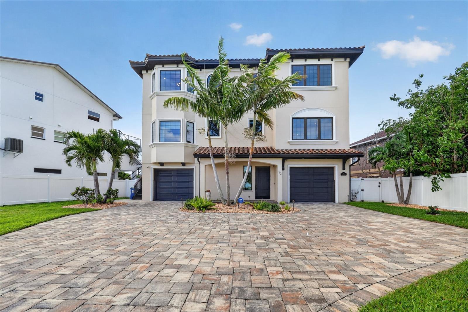 Virtually Staged. Magnificent, luxurious waterfront coastal home on Paradise Island, right off the intercoastal on Boca Ciega Bay. Designed by renowned architect Scott Hines and completed in May 2019, this gorgeous home has four full en-suite bedrooms and three covered balconies overlooking a scenic, dolphin-filled bay, complete with a dock that extends 40 ft into the water and a heavy-duty, high-speed 13,000-pound Neptune boatlift. Boat to the Gulf for awe-inspiring sunsets in minutes or walk five blocks to the white sand beaches of Treasure Island for swimming, sunbathing, and drinks on the beach (The Jeanneau French-made boat is available for purchase). The home’s ground level includes a huge 4- to 5-car garage with an electric-car charging port and plenty of space for tools, art projects, or table tennis. Nights are lit by high-end landscape yard lights and LED multicolor in the heated Pebble Tec saltwater pool and hot tub. Grill the fish you catch on your dock in a high-end outdoor kitchen, equipped with a FireMagic oversized grill and refrigerator, plus a sink, and a granite countertop. Watch sports or movies from the hot tub or the kitchen table on the high-end Samsung Terrace-brand TV. Take the stairs or elevator to the second level, where you will step into an open-concept space with a superb Chef's Kitchen to the right that features custom solid hardwood cabinetry, designer luxury countertops, Kitchen-Aid appliances, 2 Islands and a Wine/Beverage Center, including an Ice Maker, two dishwashers, and a butler’s pantry, that completes the masterpiece kitchen. To the left, set up your family space for watching TV or for a panoramic view of the water through the 4 glass sliding doors leading to your luxurious covered patio. The level includes a breakfast area off the kitchen, and a bonus room that may be a formal dining room or an office. A half bath is in this space. One en-suite bedroom with a beautiful water view of Boca Ciega Bay completes the second level. Take the elevator or stairs up to the third floor to find three more en-suite bedrooms, all with amazing water views. One is complemented by floor-to-ceiling cabinets and shelves, making it an excellent work-from-home office. Two of the bedrooms open to a large, covered patio with engaging water views. And in the middle of the floor, enjoy a large bonus room for a “man’s cave” or crafts room, that also opens to the balcony. Enjoy privacy with the high-end custom Hunter Douglas drapes/blinds. The majestic master suite boasts stunning water views from both sides, separate his/her closets, and an exquisite master bath with a spacious custom shower and an elegant soaking tub. Enjoy natural stone, hardwood, and Italian porcelain flooring, designer fixtures, and spectacular architectural appointments throughout your new home. The home is freshly painted inside and outside. The property is protected from flooding by new state-of-the-art flood panels and a new seawall. The house has a whole-home water filtration system and a drinking water filter in the kitchen. Come visit this exceptional waterfront home with its modern design and breathtaking views, elegant finishes, and supreme outdoor living spaces! Walk out on your dock and look up at the planets and be kissed by the bright stars at night. Imagine swimming with the dolphins off your private dock and paddleboarding from cove to cove. You’ll soon be living in paradise, on Paradise Island, just off the coast of St. Petersburg, Florida.