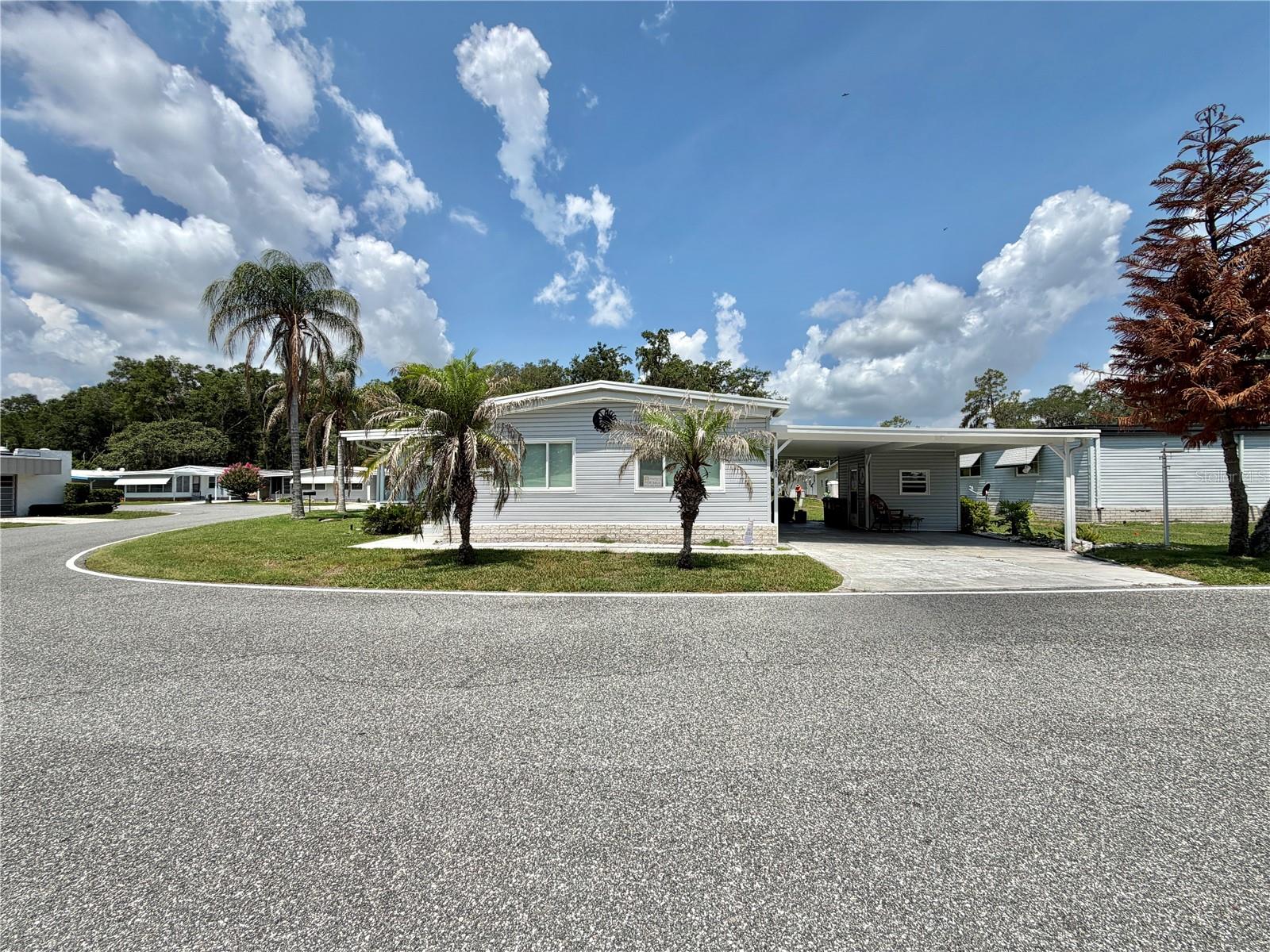 At last, the home you’ve been waiting for in Hawthorne at Leesburg! Situated on a premium corner lot, this beautifully maintained, tastefully furnished home offers fantastic lake views and exceptional value. Relax in the Florida room while enjoying peaceful water views and stunning sunsets from the comfort of your home. The spacious floor plan features a coastal-inspired primary suite with a walk-in closet and en-suite bath with a walk-in shower. A guest bedroom can easily serve as a home office or hobby room, and the guest bath includes a tub for added convenience. The fully equipped kitchen offers a cooktop, microwave, double oven, ample cabinetry, and generous workspace. An in-home laundry area with a full-sized washer and dryer adds everyday convenience, while beautiful window treatments provide warmth and charm throughout. Recent updates include upgraded windows (2010), durable exterior vinyl siding, a new roof (2015), and an HVAC system (2015), providing peace of mind for years to come. An extra-wide carport, desirable corner-lot location, and beautiful lake views complete this move-in-ready gem. Don’t miss this opportunity to enjoy comfort, convenience, and one of the most scenic settings in Hawthorne at Leesburg!.............Hawthorne at Leesburg is an active, resident owned, 55+ cooperative, waterfront, gated community, with beautifully landscaped grounds, lakes with illuminated fountains and a relaxing and comfortable gazebo. The affordable monthly maintenance fee of $397 includes water, sewer, lawn mowing, private emergency services and storage space for recreational vehicles, boats, trailers and much more! The beautiful clubhouse is complete with a full-time program coordinator, more than 100 different activities and seating for 550. It has a hospitality lounge, card rooms, craft rooms, billiard room, fitness center, library, fine arts room and many more. There is excellent fishing, outdoor geo-thermally heated pool and two enclosed therapeutic pools. Hawthorne boasts a private marina monitored by an electronic security system with over 120 boat slips and access to the Harris Chain of Lakes and beyond.