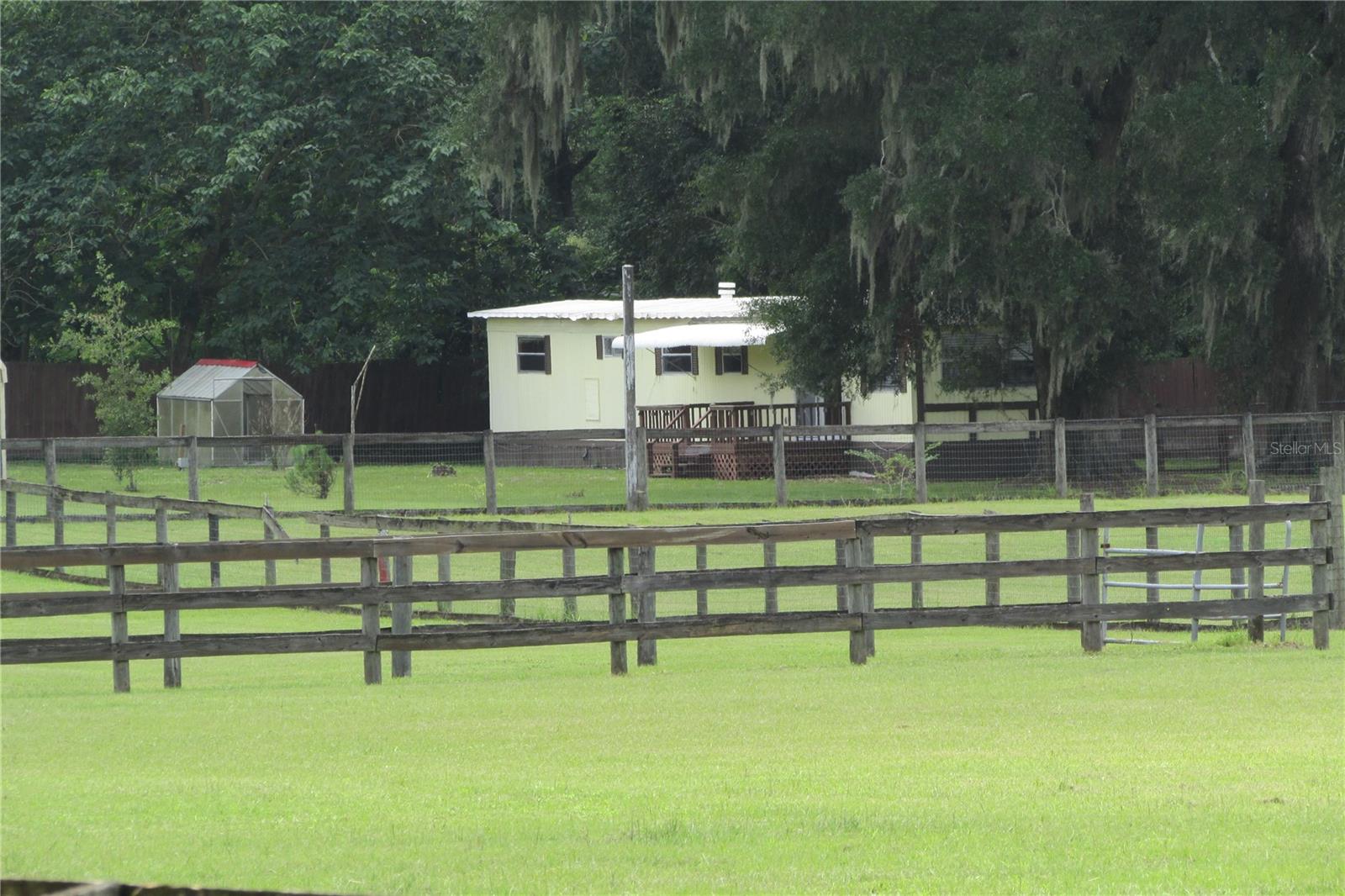 Beautiful 6 Acres with lush pastureland in NW Marion County, FL.  Property features a 1,560 SF Barn with concrete floor, 200 amp service, water, roll up door, etc.  Barn was a horse barn at one time and has been converted for storage of cars, farm equipment or potential for business purposes.  Property has 2 stall frame barn with feed/tack room, air conditioned shed and 3 large paddocks with water.  There is a light and bright move-in ready 1BR/1BA 1980 mobile home with living area, kitchen with abundance of cabinet space, inside laundry room w/storage and closet space and 1 large bedroom and bath with tub shower combo with detached 2 car carport and grow house nearby.  There is a 2nd well and septic and power ready for your new home or motor home/5th wheel(s).  Great primary residence, rental property or business potential.  Come join us in the Sunshine State and enjoy the weather year round.  Property 20 minutes from HITS, 5 minutes from I-75 and central to Gainesville for easy communite.