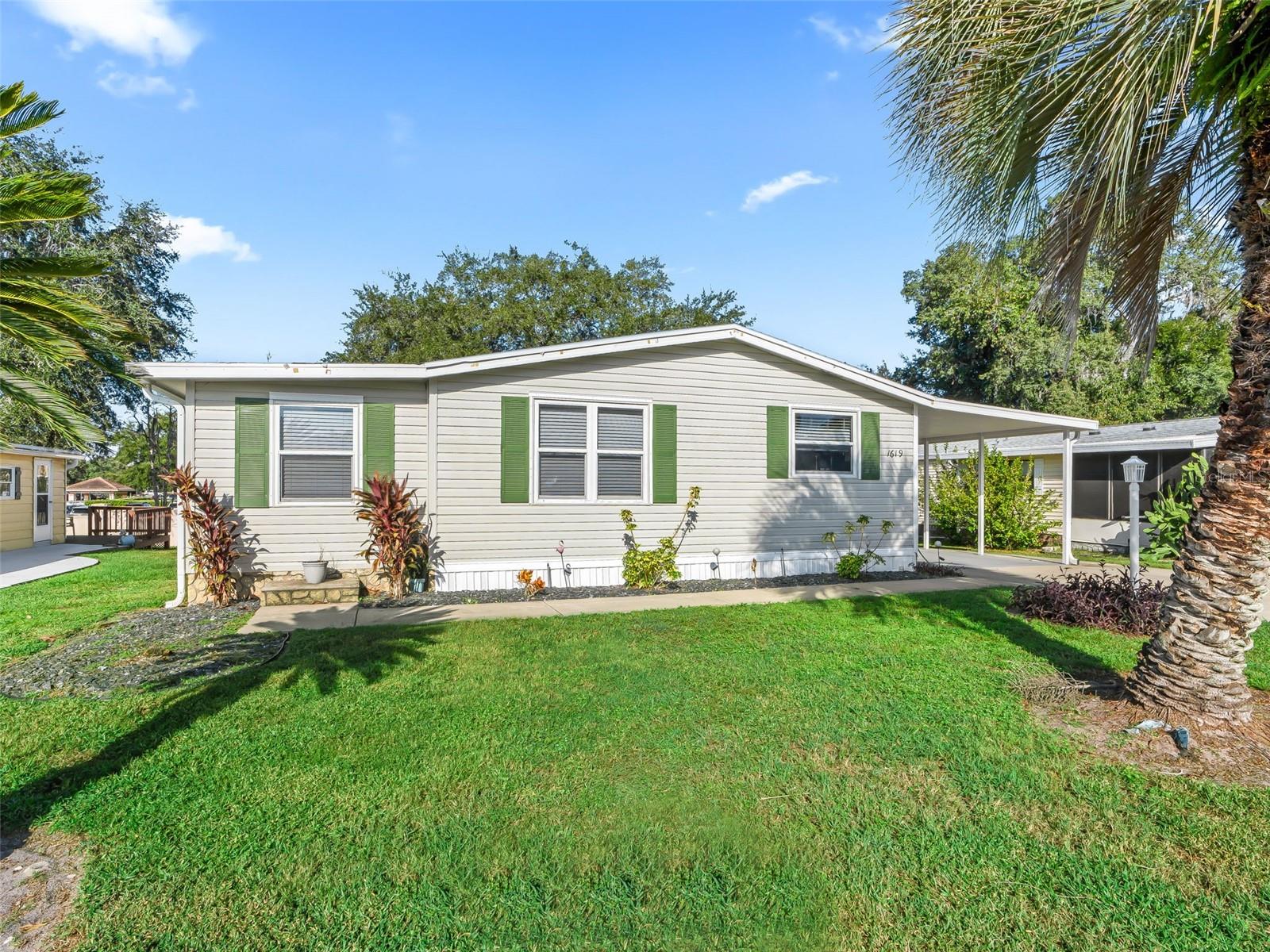 Turn-Key 2/2 Manufactured Home in Country Club Hills. This wonderfully maintained and modern turn-key 2-bedroom, 2-bath manufactured home features a newer roof installed in 2023. Situated in the highly desired Village of Country Club Hills, the property offers privacy with no homes located behind it. Residents will enjoy easy access to excellent golf courses, swimming pools, and recreation centers, all just minutes away. The home is conveniently close to Spanish Springs Town Square and is positioned along the Highway 27/441 corridor, providing an abundance of nearby shopping opportunities. Inside, the home boasts a host of modern updates and amenities. The kitchen is equipped with white cabinets accented by decorative hardware, granite countertops and tile backsplash, and stainless-steel appliances. Laminate flooring extends throughout the entire home, creating a cohesive and stylish look. Both bathrooms, as well as the hall desk and buffet area, feature granite countertops for a touch of elegance. The spacious primary suite is beautifully furnished and includes vaulted ceilings and a large walk-in closet. The primary bathroom offers ample space and a walk-in shower for convenience and comfort. The guest bedroom also features vaulted ceilings and a generous closet, making it an inviting space for visitors. Designed for entertaining, the open layout of the living and dining area is ideal for hosting family and friends for any occasion. A bonus area provides the perfect spot for card games, hobbies, or a round of darts. From this space, step into the private screened-in lanai to enjoy a relaxing evening. The golf cart garage includes a laundry area complete with a washer and dryer, as well as plenty of room for storage. The covered patio and carport have been freshly painted, adding to the home's overall appeal.