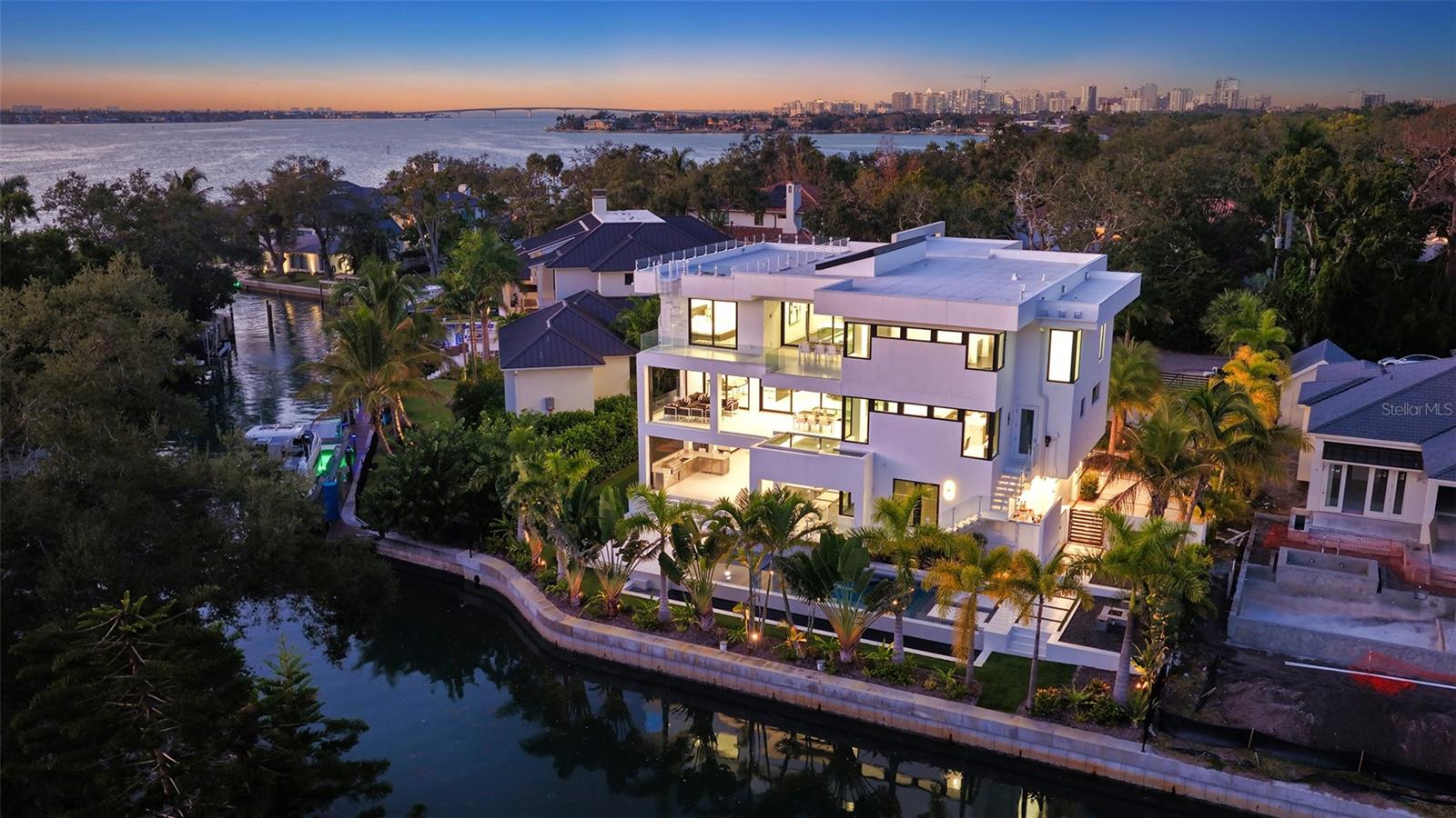 Stunning waterfront three story, coastal modern, single-family waterfront home is the perfect blend of comfort and luxury located in the treasured Cherokee Park neighborhood. Nestled on a street adorned with majestic oak and canopy trees, this exceptional property offers both privacy and grandeur. As you approach this generous lot, you'll be greeted by an electric gate entryway. Choose to park in either the detached two-car garage beneath the guest house or the hidden 6-8 car garage on the side of the house. The garage level features a private gym with a bathroom and an extraordinary outdoor living space that includes both covered and uncovered areas, a stainless steel outdoor kitchen, and a fire pit. Entering the home, you're captivated by a glass box foyer entryway with a custom staircase and state of the art glass elevator. There is also an entryway through the 6+ car garage leading to the elevator. The spacious second-floor living area boasts an open floor plan perfect for any event. The elegant great room features a custom glass floor and firebox, leading to a beautiful open kitchen with custom cabinets, waterfall stone countertops, and Subzero and Wolf appliances. Adjacent to the kitchen is a bonus room and an open yet private dining room, ideal for a wine collector with its floor-to-ceiling glass wine cellar that doubles as an art piece. Behind the kitchen cabinetry, you'll find a separate sizable pantry and laundry room. This floor also features a beautiful balcony accompanied by a glistening hot-tub/dipping pool that waterfalls into your main pool. Make your way to the third story to find 4 on suite bedrooms and a second laundry room. The primary bedroom offers an expansive layout that seamlessly blends comfort and elegance. The true highlight is the gorgeous balcony overlooking the pool that leads to a staircase up to the breathtaking rooftop. From here, you will enjoy panoramic views of the spectacular Sarasota. Whether you’re hosting a sunset soiree or savoring peaceful morning coffee, this rooftop oasis provides an extraordinary vantage point. This seamless indoor-outdoor flow and the captivating scenery make this property a true gem for those seeking both luxury and tranquility in a prime location.