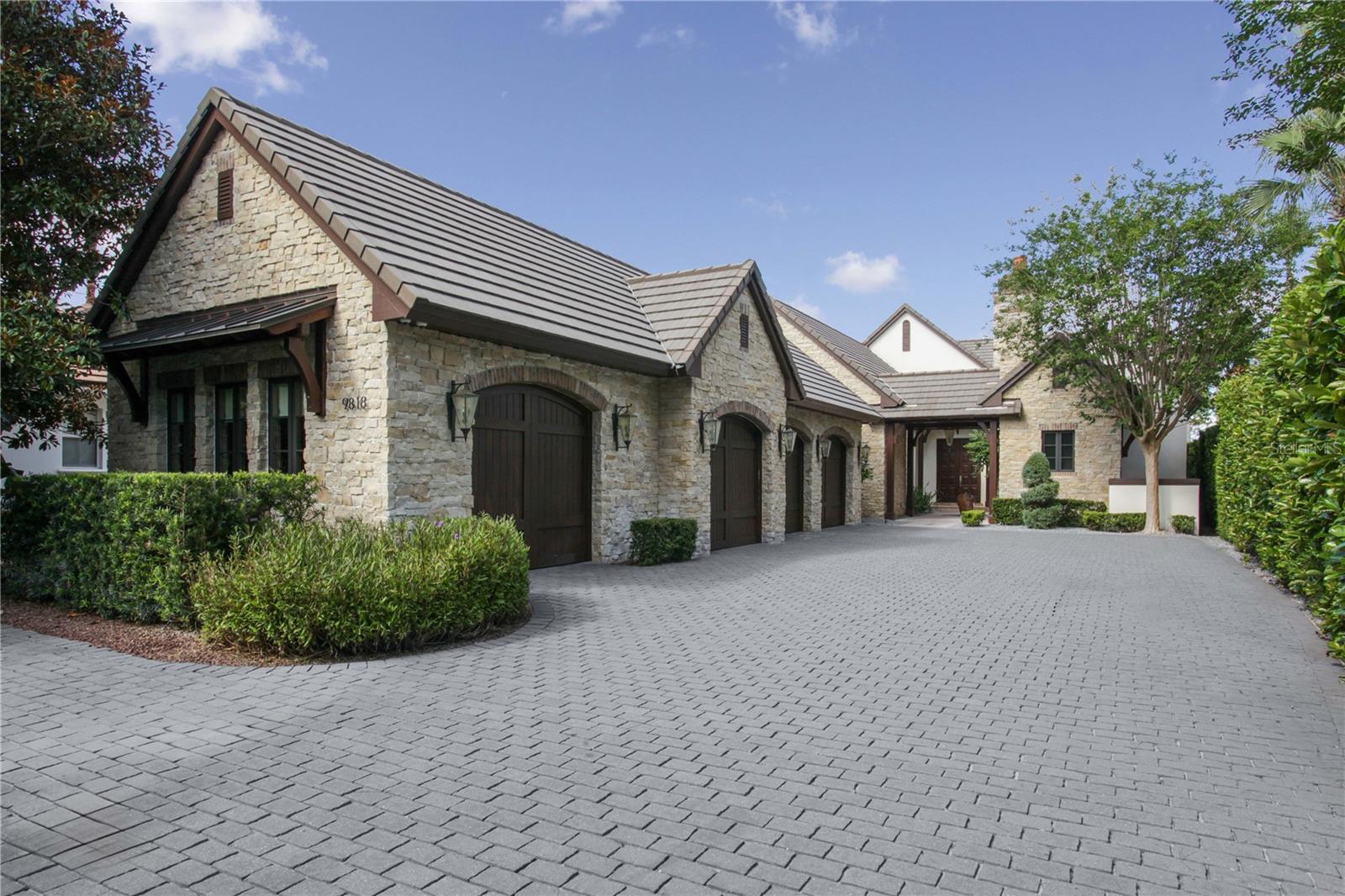 Located along Hole #4 of Lake Nona’s prestigious golf course, this contemporary English cottage includes four bedrooms, five full and one half bathrooms among its 5,646 square feet.
Authentic stonewalls and timeless wood detailing welcome you into the courtyard entrance of this single-story floor plan. The modern-day luxuries and high-end finishes of this home, combined with its traditional architectural details, create a stunning transitional style.
An open-concept great room, filled with natural light, features meticulous details, including marble floors, an exposed, wood-beamed ceiling, a built-in entertainment center and multiple sets of glass doors that lead to the outdoor living area.
The gourmet kitchen offers a large center island with beverage sink, a caterer’s kitchen, a hidden walk-in pantry, double ovens, and a six-burner gas cooktop and hood.
Located in its own private wing, the master suite comes fully equipped with a morning bar, dual wardrobes and vanities and overlooks breathtaking views of the golf course.
Outdoor entertaining comes easy with the home’s covered lanai, summer kitchen and marble pool deck. The unique courtyard pool and spa is enclosed with a glass railing.
The highlight of this residence is a second-level covered lanai with retractable screens and invites the opportunity to fully enjoy Florida’s temperate climate.
Additional features include: Family room with wet bar & wine refrigerator; Home office; Fitness room; Three-car garage with attached air-conditioned golf room; Air-conditioned fully finished attic.