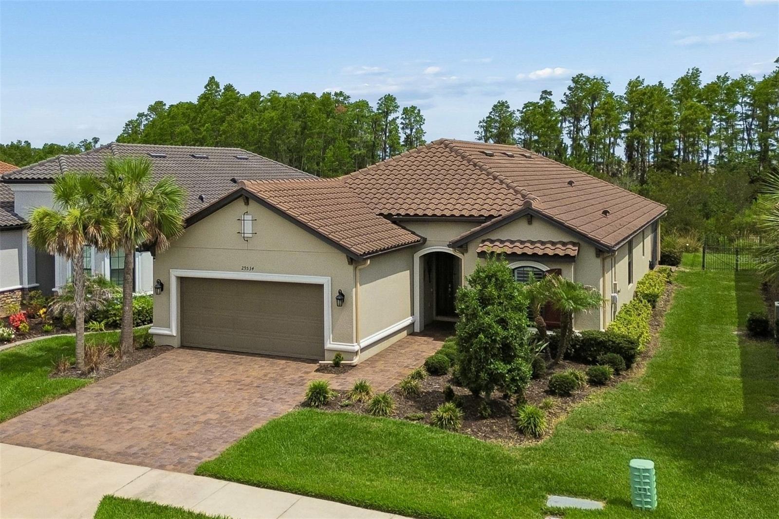 Welcome home! Enjoy the luxury living in this Esplanade of Tampa located in a maintenance free, 55+, gated community. Why wait to build when you can enjoy this Lazio dream home now.  This home features 2376 SF, 3 bedrooms, 3 baths, an office/flex room, and a 3-car tandem garage.  You will notice the attention to detail as you enter custom glass door to an open floor plan, extended gourmet kitchen overlooking a large family room, featuring 42” solid wood cushion close cabinets with crown molding, quartz counters with custom backsplash, upgraded stainless steel Bosch appliances, Wi-Fi enabled oven-microwave combination, enormous island, pendant lights, and a custom walk-in pantry. The oversized owner’s suite has custom millwork, dual sinks, a custom designed built-in closet, and tray ceiling with crown molding. The family room boasts coffered ceilings with crown molding, power blinds, custom millwork, and lots of natural light. Bedroom 2 has an ensuite bath and custom walk-in closet.  Office has custom built-ins desk, millwork, and bench. This one-story Taylor Morrison custom home has an open floor plan with an extensive list of upgrades. These upgrades include, but are not limited to extended eat in kitchen, designer tile floors throughout, motorized blinds, custom designer drapes, 8’ doors, quartz counters in bath, extended paver driveway, tile roof, large laundry room with cabinets, tandem garage with epoxy floors, and a water softener loop. The premium conservation lot has no rear neighbors. The extended paver covered lanai features a floor to ceiling stone linear fireplace, outdoor kitchen and custom shades that provide privacy and wind protection. Esplanade of Wiregrass Ranch has a luxurious upscale club house with full-time lifestyle and fitness directors. The Venue includes a resort style pool, hot tub, cabanas, dog park, state-of-the-art 24-hour fitness center, billiard/card room, and spa room. For active outdoor entertainment there is a firepit, tennis, pickleball, bocci, and large meeting/gathering area.  Esplanade also includes worry free yard maintenance, reclaimed water and Spectrum TV and internet package included in fees. This home is located only minutes from shopping, I-75, hospitals, restaurants, recreation, and entertainment.  Come see for yourself this exquisite residence and relax, you are home. Please see walkthrough and 3D tours.