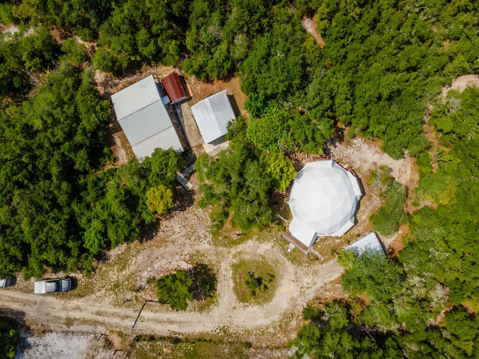 30810 NE 78 Street, Salt Springs, FL 32134
Main Geodesic Home - 2 Bedrooms | 3 Bathrooms | 1,263 Sq Ft | 
Apartment/Game Room - 1 Bathroom | Full Kitchen  
Garage | 2.39 Acres

Perched atop one of the highest elevations in Northeast Marion County, this one-of-a-kind property is nestled in the unique and highly sought-after Yellow Bluff area of Salt Springs. Surrounded by variety trees and natural beauty, this private 2.39-acre retreat offers a rare opportunity to own a distinctive Geodesic Dome home unlike anything else on the market.

Built in 2002, the home features 1,263 square feet of living space, blending modern updates with architectural character. Inside, you'll find beautiful oak hardwood flooring throughout the main living areas, complemented by tile and laminate flooring. The open and airy floor plan is enhanced by soaring ceilings and abundant natural light.

The kitchen was completely updated in 2021 and showcases IKEA cabinetry, updated countertops, stylish backsplash, abundant storage, a convenient sit-at bar, and all appliances included. Two sets of French doors open onto spacious wood decks overlooking nothing but woods and privacy, creating the perfect setting for morning coffee, entertaining guests, or simply enjoying the peaceful surroundings.

The main-level bedroom is generously sized and features a sliding glass door leading to a private deck where you can enjoy breathtaking western sunset views. The adjacent bathroom includes a relaxing soaking tub and updated vanity.

A spiral staircase leads to the open loft bedroom, offering a bright and inviting retreat complete with a built-in desk area and private bathroom featuring a jetted tub/shower combination.

Additional conveniences include an indoor laundry area with washer and dryer included.

A short walk from the main home brings you to a versatile 24' x 24' apartment/game room, complete with a full kitchen, full bathroom, tankless water heater, and window air conditioning units. This flexible space is ideal for guests, extended family, hobbies, a home office, or recreational use.

For those needing storage or workshop space, the property also includes a 20' x 20' insulated metal garage equipped with both 110 and 220 power, roll-up door, and plenty of workspace. Additional improvements include a two-car metal carport, 8' x 10' metal storage shed, and extensive wooded acreage offering exceptional privacy and room to explore.

Located in the heart of the Ocala National Forest, you'll enjoy immediate access to some of Florida's best outdoor recreation. Salt Springs, Lake George, the St. Johns River, and countless natural springs are all nearby. The area is renowned for boating, fishing, kayaking, hunting, horseback riding, hiking, and miles of ATV and SxS trails.

Whether you're seeking a full-time residence, vacation retreat, income-producing opportunity, or simply a unique property surrounded by nature, this remarkable Yellow Bluff retreat delivers a lifestyle that is truly impossible to duplicate.

Schedule your private showing today and experience one of the most unique properties in Salt Springs.