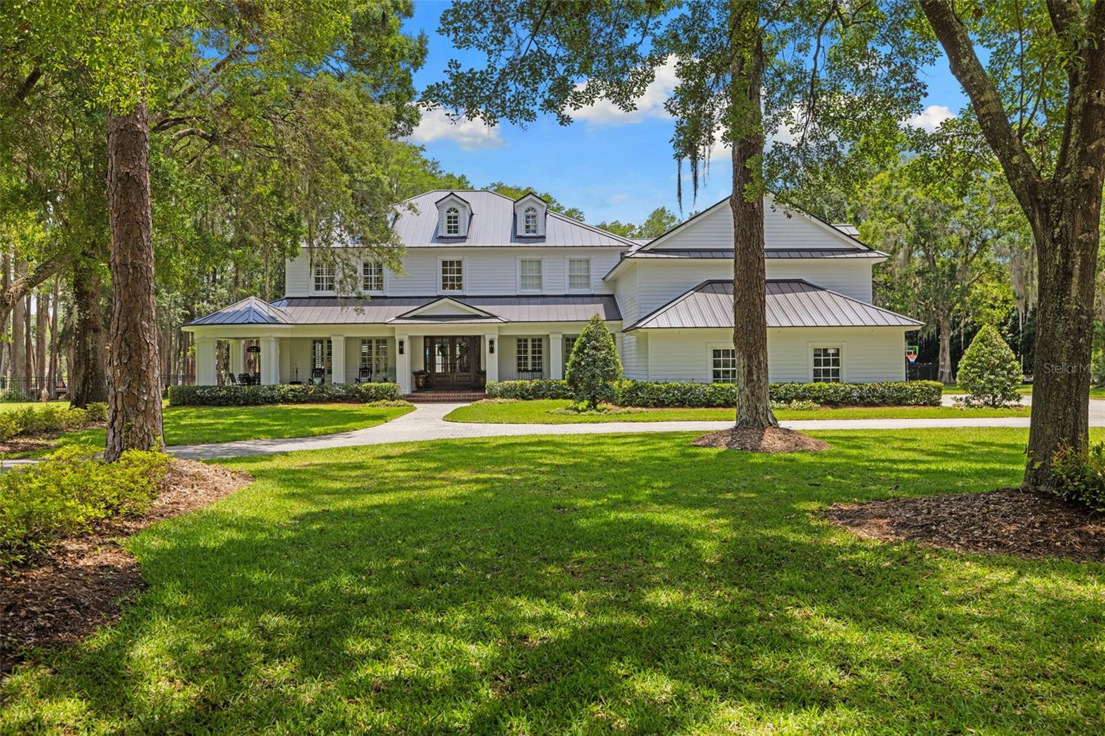 Classic, timeless, and effortlessly luxurious — welcome to your dream lifestyle at 18562 Council Crest Drive, where refined lakefront living meets the perfect Tampa Bay location. Behind the gates of the exclusive Council Crest community, surrounded by 4.69 private acres with 329 feet of frontage on Lake Martha, this extraordinary estate blends elevated design/upgrades, resort-style outdoor living, and serene waterfront beauty. The atmosphere is immediate: quiet, private, and framed by mature live oaks and cypress — worlds away from the city, yet minutes from Tampa's best dining, shopping, interstates, airports, and beaches, and zoned for top-rated Steinbrenner High School. Spanning over 7,260 SF across three levels with a private elevator, the home (built 2009) has been extensively upgraded by the sellers for elevated living and unforgettable entertaining. Beneath a newer metal roof (2022), new solid wood doors open to a foyer and a redesigned, open staircase. Rich wide-plank engineered hardwood floors flow under soaring coffered ceilings and crisp millwork. The layout offers 5 bedrooms, 4.5 baths, a 4-car garage, dual primary suites, a theater room, formal living and dining spaces, and a stunning double-island kitchen — two stone islands, custom cabinetry, brick backsplash, Wolf gas range, Wolf appliances, Sub- Zero fridge,  built-in coffee maker, and a breakfast room wrapped in custom wallpaper. The living room anchors with a custom entertainment wall and brick fireplace. Every room has been enhanced with designer-level upgrades — custom carpentry, statement lighting, designer wallpaper, renovated baths, and surround sound inside and out. The dual primary suites include a main-level suite with new brick flooring and a fully updated pool bath, plus a hotel-worthy upper suite with spa bath, freestanding tub, glass shower, dual vanities, and a massive walk-in closet with its own center island. Lifestyle spaces include a theater room, spacious guest suites, a bonus/gym room (currently the 5th bedroom), and an expansive third-floor loft that serves as an air-conditioned storage level and bonus space. Outside, the estate becomes a private resort. A spectacular 38-foot heated saltwater pool and spa with oversized sun shelf centers a travertine terrace built for entertaining. The upgraded cabana features a brick fireplace, mounted TV, speakers, tongue-and-groove ceilings, and a matching metal roof, all framed by lake views. A new private covered dock with electricity overlooks Lake Martha — perfect for fishing, sunsets, and peaceful mornings on the water. Significant investment includes a 2022 metal roof, 2022 water treatment system, newer pool equipment, tankless gas water heater, 500-gallon propane, an expanded backyard (˜38 truckloads of fill and nearly $50,000 in sod), extended lanai decking, new front doors, and extensive interior and exterior renovations throughout. Wake to peaceful lake views, fish from your private dock, and entertain under the cabana at sunset — all while enjoying complete privacy minutes from the energy of Tampa Bay. Set within a small community of just 10 homes, 18562 Council Crest Drive is more than a home; it is a fully curated luxury lifestyle of beauty, privacy, and timeless elegance in one extraordinary address.