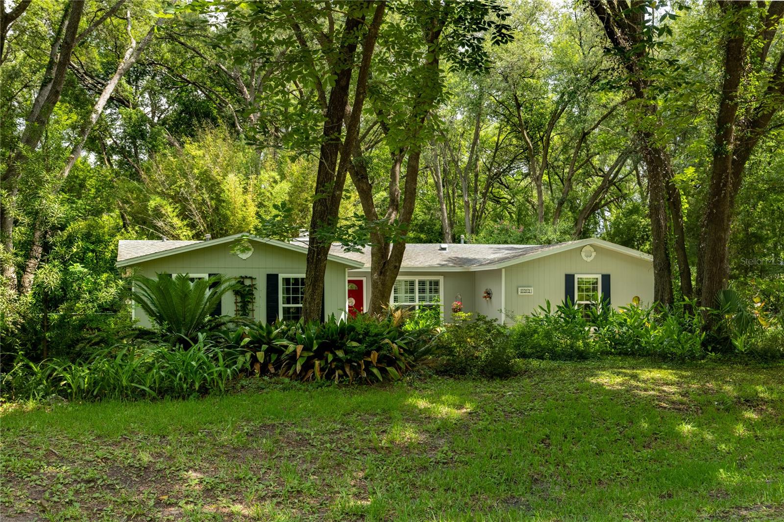 Just listed for sale a private retreat pool home on 1.24 acres in SW Gainesville's Sunny Acres. This three bedroom, two bathroom home was built in 1980 and has been well maintained and updated throughout. Nestled amongst a grove of Live Oaks, this home offers modern amenities combined with a home filled with light and privacy. Sunny Acres is located in unincorporated Alachua County and has no HOA dues. Just 8 miles to the University of Florida and located conveniently to area shops and restaurants, the home feels secluded and private, but is still close to everything. Enter off the covered front entry to an open Great Room with tile floor, wood paneled accent wall, wood burning fireplace and floor to ceiling window. Off the Great Room is a dining area that opens to the Kitchen. There are French doorsthat lead to the backyard patio and pool. Just off the dining area is the updated Kitchen with breakfast bar, granite counter tops, maple wood cabinets, plantation shutters, brand new stainless steel appliances including a gas range, microhood and side by side refrigerator. Off the Kitchen is the laundry room with washer and dryer, laundry tub and additional cabinetry for storage and access to the two car, side entry garage, To the left of the front door is the main hall with two guest bedrooms and a guest bathroom. The bedrooms have updated bamboo floors, floor to ceiling windows and ceiling fans. The guest bathroom has updated tile, plumbing fixtures including sink and toilet and new lighting. At the end of the hall, to the rear of the home is the master bedroom with walk-in closet and en suite bathroom. The large master suite has bamboo floors, ceiling fan and French doors to the rear yard and pool. The master bathroom has updated custom tile, vanity, plumbing fixtures and lighting. The lot is 1.24 acres. The rear yard is fenced. The beautiful pool has a large cool deck, brick walkways and offers a lush private setting with flowering plants, butterfly garden, shrubs and mature trees. The backyard has sheds, chicken coop and small separate fenced run. The updates include a brand new HVAC system with propane furnace in 2026. The roof was installed in 2016. There is a well and a water purification system. The septic system was pumped and inspected in 2026. The home is serviced by Clay Electric and has access to high speed fiber optic. Zoned for Archer Elementary, Kanapaha Middle and Newberry High Schools. This pool home is turnkey and offers a fantastic SW Gainesville location.