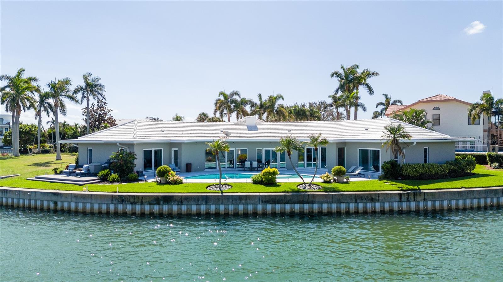 Welcome to your dream waterfront oasis in the prestigious Bayway Isles, a private gated community renowned for its prime location just minutes from the stunning St. Pete Beach, Fort DeSoto Park, and vibrant downtown St. Petersburg. This exceptional mid-century modern home, originally built in 1965 and meticulously modernized over the past eight years, is perfectly positioned on one of the most sought-after homesites in the area.



As you enter, you are greeted by an exquisite custom terrazzo sunrise design in the foyer, leading you into the elegant formal living and dining rooms, adorned with the same beautiful terrazzo flooring. Impact-rated sliding glass doors seamlessly connect these spaces to the pool area, offering breathtaking, unobstructed views of the expansive 165 feet of waterfront that surrounds the home. The large lot enhances the property’s appeal as does the semi-circular design of the house that maximizes natural flow and affords stunning water vistas from nearly every room.



This luxurious residence features four generously sized bedrooms, each with its own attached bath for ultimate comfort and privacy. The formal living room, with its panoramic water views and original wood-burning fireplace framed by a stunning copper fluted chimney breast, serves as a perfect gathering place for family and friends. 



Culinary enthusiasts will appreciate the modernized kitchen, designed for both functionality and style, equipped with three ovens, an induction cooktop, and a custom range hood. A cleverly hidden pantry door leads to the laundry/mud room, adding convenience and additional storage. Off the kitchen is a large family room that affords a space to relax while still being a part of what’s happening in the kitchen.



The thoughtfully designed split bedroom plan places the primary suite in a serene setting, ensuring a peaceful retreat. This spacious haven boasts sweeping water views and an opulent primary bath featuring a large steam shower, a second walk-in shower, and a standalone soaking tub. The custom-built primary closet is a dream come true, offering ample space and thoughtful organization for your wardrobe.



On the opposite side of the home, three additional bedrooms, each with attached baths, provide excellent accommodations. The fourth bedroom doubles as a potential secondary suite, complete with sliding doors that open to the pool and stunning water views. It’s attached bath conveniently serves as a pool bath with a private entrance from the outdoor area.



Step outside to discover a beautifully sized pool that was recently refinished, along with a pool deck perfect for relaxation and entertainment. The pool deck is shaded throughout the day for your comfort. An adjacent grilling and seating area offers additional spaces to savor the idyllic waterfront lifestyle this remarkable home provides.

This luxurious property is not just a home; it’s a lifestyle waiting for you to embrace. Welcome to Bayway Isles, where your waterfront dreams come true.