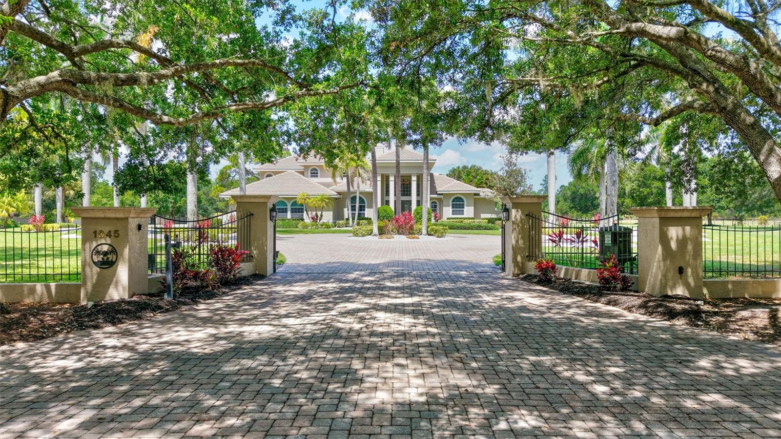 Exclusively situated on 5.1 expansive acres, this custom-built Sarasota estate is masterfully designed as a fully self-contained private family enclave. Completely insulated from the outside world, the property is introduced by a long, palm-lined approach and a sweeping circular paver driveway, where total privacy and the Florida lifestyle are immediately evident. 

The primary residence spans 6,721 square feet of luxurious living space, making a grand architectural statement the moment you enter a foyer flanked by towering 24-foot ceilings. The estate showcases abundant natural light, French doors and rich maple built-ins throughout. At the heart of the home, the epicurean kitchen features elite millwork by Campbell Cabinetry, a spacious L-shaped island, a butler's pantry, and professional-grade Wolf and Sub-Zero appliances—including dual ovens and a specialized warming drawer.

The fluid floor plan offers unmatched versatility, hosting a formal dining room with custom tray ceilings, a magnificent Great Room with fireplace under a 22-foot ceiling, two separate private offices, one of which has a wood-beamed cedar ceiling, and a spectacular, approximately 1,000-square-foot recreation wing outfitted with its own full kitchen and bath. Retreat to the first-floor owner’s suite, an elegant sanctuary featuring a private sitting area, a spa-inspired bath, and peaceful views overlooking the estate and pool.

Outdoor living captures the estate-style relaxation, with a vast screened lanai and a sparkling saltwater pool overlooking open lawns and mature perimeter landscaping that naturally buffers the property. Recreational amenities are premier, featuring an integrated basketball court and a dedicated section of the driveway already marked for pickleball. The sprawling grounds serve as a grand retreat, anchored by an exceptional detached multi-car garage pavilion. Perfect for collectors or specialized hobbyists, this secondary structure features oversized 11-foot doors, a dedicated RV and boat storage area, carport, and a versatile, fully plumbed auxiliary suite with a full shower, ideal as a detached executive workspace or private retreat.

Unequaled in structural integrity, the home functions as a fortified private fortress engineered with poured-concrete construction, comprehensive rebar reinforcement, elevated foundation, standby generator,  salt-and-carbon water filtration system, separate sprinkler well, and advanced 13-camera security system. Providing space perfectly zoned to accommodate equestrian pursuits, miniature horses, alpacas, or exotic hobby collections, the OUE1 acreage offers absolute lifestyle freedom, all while being securely situated in Flood Zone X, with an exceptionally low annual HOA fee and no CDD. Positioned at the absolute center of convenience, the estate sits just 3.5 miles from Waterside Place, 4 miles from the University Town Center district, and 4.5 miles from Main Street Lakewood Ranch—placing championship golf courses, premier dining, luxury shopping, and active community calendars right at your fingertips. Surrounded by the tranquility of your private sanctuary, allure of downtown Sarasota and world-renowned Gulf Coast beaches await just moments beyond your gates.