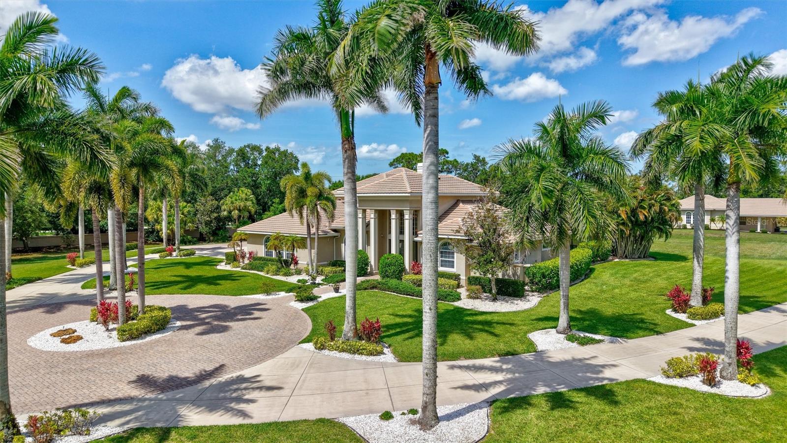 Beyond a long, palm-lined approach awaits a private Sarasota estate, exclusively situated on 5.1 expansive acres and designed as a self-contained family enclave with a sweeping circular paver driveway welcoming you home, where privacy and the Florida lifestyle begin.

The primary residence spans 6,721 square feet, making a grand architectural statement the moment you enter a foyer flanked by soaring 24-foot ceilings. Abundant natural light, French doors, and rich maple built-ins complement a versatile floor plan centered around a Great Room with a fireplace beneath a soaring 22-foot ceiling, a formal dining room with custom tray ceilings, two private offices—one with a wood-beamed cedar ceiling—and an approximately 1,000-square-foot recreation wing complete with its own full kitchen and bath.

At the heart of the home, the kitchen showcases Campbell Cabinetry, a spacious L-shaped island, butler's pantry, and professional-grade Wolf and Sub-Zero appliances, including dual ovens and a warming drawer.

The first-floor owner's suite offers a private sitting area, spa-inspired bath, and peaceful views overlooking the estate and pool.

Outdoor living centers around a 1200 ft. screened lanai area including a saltwater pool overlooking expansive lawns and mature landscaping that naturally buffers the property. Recreational amenities include a basketball court and a dedicated section of the driveway already marked for pickleball.

The grounds are anchored by a detached multi-car garage pavilion designed for collectors and hobbyists, with oversized 11-foot doors, dedicated space for RV and boat storage, covered carport, and a fully plumbed auxiliary suite with a full bath—ideal as a private office, guest retreat, or flexible workspace.

Built with poured-concrete construction, comprehensive rebar reinforcement, an elevated foundation, standby generator, salt-and-carbon water filtration system, separate sprinkler well, and a 13-camera security system, the home was engineered for lasting structural integrity.

The OUE1-zoned acreage accommodates equestrian pursuits, miniature horses, alpacas, and other hobby livestock while offering the advantages of Flood Zone X, an exceptionally low annual HOA fee, and no CDD.

Positioned at the center of it all, the estate sits just 3.5 miles from Waterside Place, 4 miles from the University Town Center district, and 4.5 miles from Main Street Lakewood Ranch—placing championship golf, premier dining, luxury shopping, and vibrant community events within minutes. Beyond your gates, you have the allure of downtown Sarasota, world-renowned Gulf Coast beaches, and the Sarasota International Airport all nearby your new address!