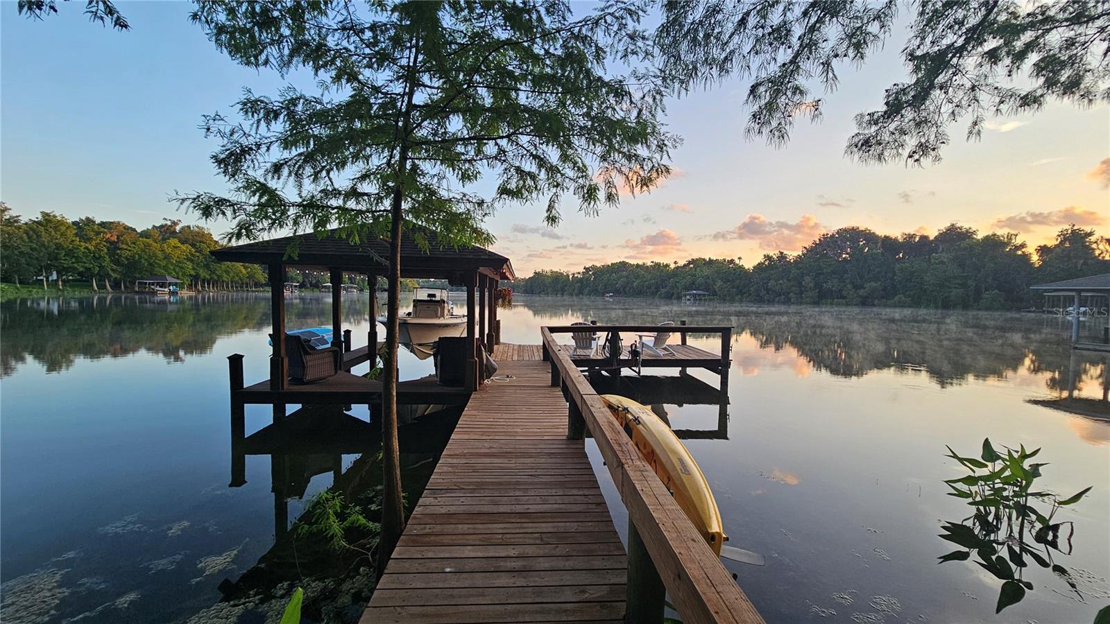 Some homes offer a view. This one offers a way of life. Nestled on approximately 1.4 beautifully landscaped acres, this extraordinary lakefront retreat seamlessly blends luxury, privacy, and nature in perfect harmony. Extensively renovated inside and out, this is far more than a home—it's a private waterfront sanctuary designed for those who appreciate exceptional craftsmanship, resort-style outdoor living, and the freedom that only a property like this can provide. Wake each morning to panoramic views of Lake Waterford, one of the area's premier ski lakes, where boating, wakeboarding, paddleboarding, kayaking, and fishing become part of everyday life. Your dock, complete with water, electricity, and a boat lift, places the lake just steps from your back door. The grounds are professionally landscaped and showcase more than 800 plants, creating a lush botanical setting filled with flowers, butterfly habitats, and fruit trees including avocado, banana, lemon, lime, grapefruit, orange, mulberry, pomegranate, and passion fruit. Mature wooded buffers surround the property, creating privacy while attracting an abundance of wildlife including deer, wild turkeys, osprey, and bald eagles. It's a setting that feels worlds away while remaining just minutes from everything. Inside, nearly every major component of the home has been thoughtfully upgraded to create a residence that feels virtually new. Hurricane-rated windows and doors flood the home with natural light. Meanwhile, the whole-house 22kW Generac generator, heavy-gauge standing seam metal roof, dual HVAC systems, and whole-house water softener provide the long-term peace of mind buyers rarely find. New flooring throughout the home, complemented by solid-core interior doors, updated trim, fresh paint, designer lighting, remodeled bathrooms, upgraded kitchen appliances. French doors open to the dedicated home office just off the foyer and the ground-floor primary en-suite features two walk-in closets, a free-standing tub, dual vanities and walk-in shower. Designed for entertaining and everyday living, triple sliding glass doors open up the interior with the screened lanai overlooking the pool and lake. The resurfaced heated saltwater pool and spa create the centerpiece of an outdoor living space, while the fully equipped outdoor kitchen—featuring a Café beverage center, Big Green Egg, and propane cooktop—sets the stage for everything from family dinners to unforgettable gatherings with friends. Practicality hasn't been overlooked. A fenced backyard, storage shed, abundant interior storage, attic decking above the garage, a 50-amp garage outlet for an EV charger or workshop equipment, and professionally illuminated landscaping complete a property where every detail has been carefully considered. Although the setting feels wonderfully secluded, the home is ideally located east of I-95, placing NSB's pristine beaches, the boutiques and restaurants of historic Canal Street, and the vibrant dining, shopping, and nightlife of Flagler Avenue just minutes away. Here, you can spend the morning on the lake, enjoy lunch downtown, catch sunset on the beach, and be home in time for dinner by the pool. Luxury isn't measured by square footage. It's measured by mornings on the lake, evenings beneath the oaks, and the feeling that you've finally found a place you'll never want to leave.