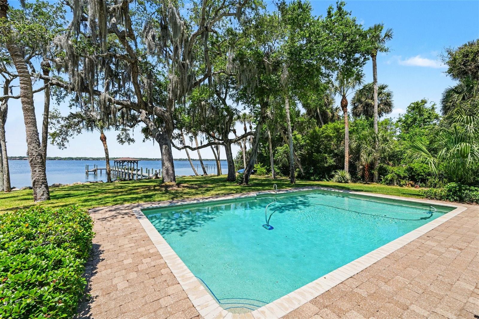 Experience waterfront living on the Space Coast in this stunning 5BR/3.5BA riverfront estate on the Indian River. A welcoming foyer sets the tone, leading to a private office, separate living room, and an open-concept kitchen, family, and dining area with custom built-ins and a cozy fireplace. The updated kitchen features a breakfast bar, cook island, newer stainless steel appliances, Corian counters, and appliance garages. Two bedrooms are conveniently located downstairs, ideal for guests or multi-generational living. Step outside to a covered porch with electric screens overlooking the sparkling pool and tranquil water views. Upstairs, the primary suite offers a private balcony, spa-like ensuite with soaking tub and walk-in shower. Additional highlights include spacious guest rooms, abundant natural light, and an oversized 2-car garage. Enjoy direct river, deep water access, with your private dock - perfect for boating, fishing, and watching breathtaking sunsets.