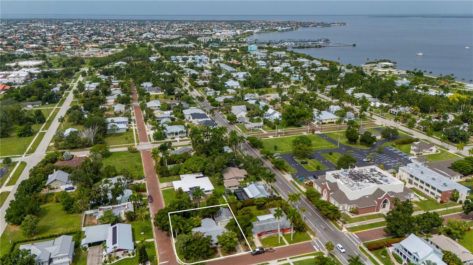 Located along one of Punta Gorda’s historic brick streets, this four-bedroom home offers distinctive Old Florida character in the heart of downtown. Mature trees and lush tropical vegetation surround the property, creating a private, garden-like setting while keeping you close to the city’s most popular destinations. Please note, that this parcel consists of 2 platted lots! Inside, the spacious layout provides plenty of flexibility for everyday living, guests, a home office, or investment use. An oversized screened lanai with vaulted wood ceilings expands the living space and provides an inviting setting for relaxing or entertaining year-round. The detached four-car garage offers exceptional room for vehicles, recreational equipment, storage, or a workshop. From here, enjoy biking or strolling along the Harborwalk, visiting Gilchrist and Laishley parks, exploring Fishermen’s Village, or dining at nearby waterfront restaurants. With marinas, boating, the harbor, and downtown attractions just minutes away, this property presents an excellent opportunity as a primary residence, vacation retreat, or investment in one of Southwest Florida’s most charming coastal communities.