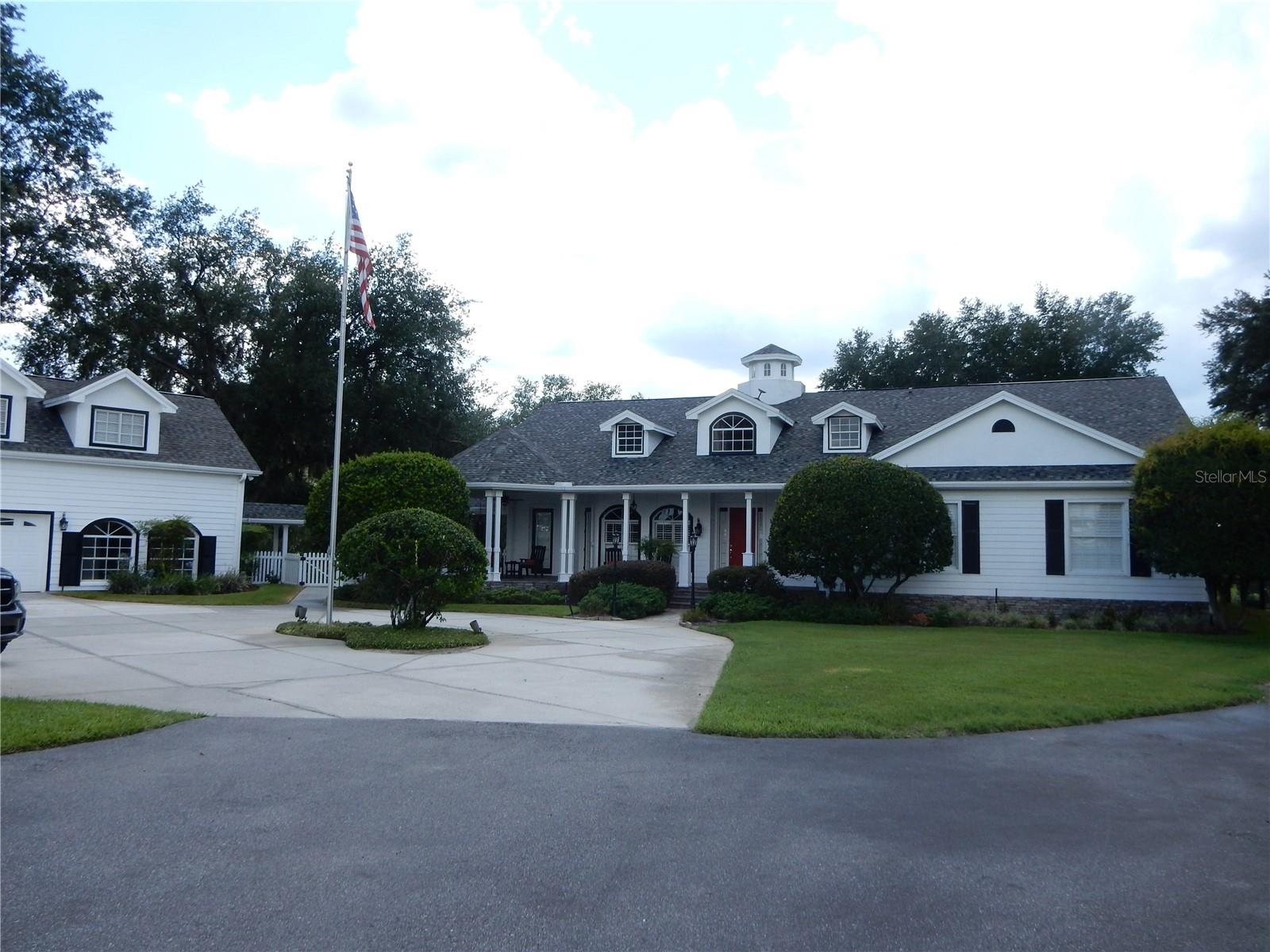 Under contract-accepting backup offers. Experience refined country living at this breathtaking estate, ideally located just minutes from I-75. The exquisite main residence offers 3 bedrooms, 2 full baths, and 2 half baths, along with an approximately 1,000-square-foot guest apartment (1 bed/1bath) above the detached garage, ideal for guests or private accommodations. Elegant interior finishes include scraped hickory wood flooring throughout the foyer, dining room, great room, and hallways, tile in wet areas, soaring ceilings, crown molding in the formal dining room and primary suite, custom shutters, and a gas fireplace in the great room. Driving through the Private gated entrance and private road is an extraordinary 15+ acre property designed for both luxury living and enjoyment. Rocking Chair Front porch with a covered area to sit and enjoy the Sunrises! Solar panels provide power to the garage apartment, generator and barn lights. The estate features horse barns, and is completely fenced and cross-fenced, and has picturesque lake views that create the perfect backdrop for unforgettable sunsets enjoyed from the expansive lanai. Designed for entertaining, the gourmet kitchen showcases custom solid wood cabinetry, granite countertops, a Sub-Zero refrigerator, wet bar, wine cooler, and an oversized island. The luxurious primary suite offers a private sitting area, crown molding, and a spa-inspired bath complete with granite counters, separate shower, Jetted-Jacuzzi tub, and spacious his-and-her walk-in closets. A standout feature of the home is the beautifully crafted cigar bar room, complete with a custom wood bar, built-in humidor, wet bar, ice maker, and ventilation system. This versatile space could also serve as a fourth bedroom. Outdoor living is equally impressive with a covered, fully tiled lanai designed for entertaining. The screened pool area features a custom-designed pool, heated spa, and lush tropical landscaping.