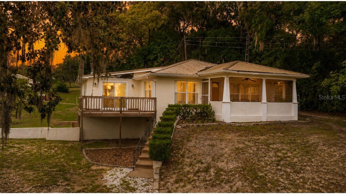Lake life begins here! Nestled on 1.03 acres with 30 feet of deeded access to beautiful Little Lake Weir, this well-maintained concrete block home offers the perfect blend of timeless character, modern updates, and the outdoor lifestyle you've been searching for. With two spacious bedrooms, two updated bathrooms, and multiple indoor and outdoor living areas, this property is ideal as a primary residence, weekend retreat, or vacation home.

Wake up to gentle lake breezes and enjoy peaceful water views from the screened porch, or unwind on the deck just off the family room while taking in spectacular sunset skies. Natural light fills the home through newer windows, highlighting the architectural details that make this property truly special, including transom windows, tongue-and-groove knotty pine accent walls, and a convenient pass-through window connecting the updated kitchen to the spacious family room. Sliding glass doors create a seamless transition to outdoor living, making entertaining family and friends effortless.

The updated kitchen and bathrooms combine modern convenience with classic charm, while newer flooring throughout adds to the home's move-in-ready appeal. Outside, mature avocado and orange trees provide a true taste of Florida living, complemented by a private rear patio perfect for grilling, relaxing, or enjoying the peaceful surroundings.

Storage and workspace are plentiful with a one-car garage located beneath the home that is perfect for a workshop, hobby space, or storing lake toys, along with two additional detached storage buildings. Whether you enjoy boating, fishing, kayaking, paddleboarding, or simply soaking in the beauty of nature, this property is designed for those who love the outdoors.

Major improvements provide peace of mind, including a new septic system and drain field (2021), complete well system (2022), water filtration system (2022), side-by-side refrigerator (2022), washing machine (2023), HVAC system installed in 2017 and regularly serviced, upgraded electrical panel (2012), and a durable metal roof installed in 2006.

Conveniently located less than five minutes from Carney Island Recreation & Conservation Area, you'll have quick access to a public boat ramp, beach, swimming area, fishing, walking trails, picnic pavilions, and waterfront recreation. If you've been dreaming of a property that offers space, privacy, water access, and the best of Florida lake living, this exceptional Little Lake Weir home is ready to welcome you home.