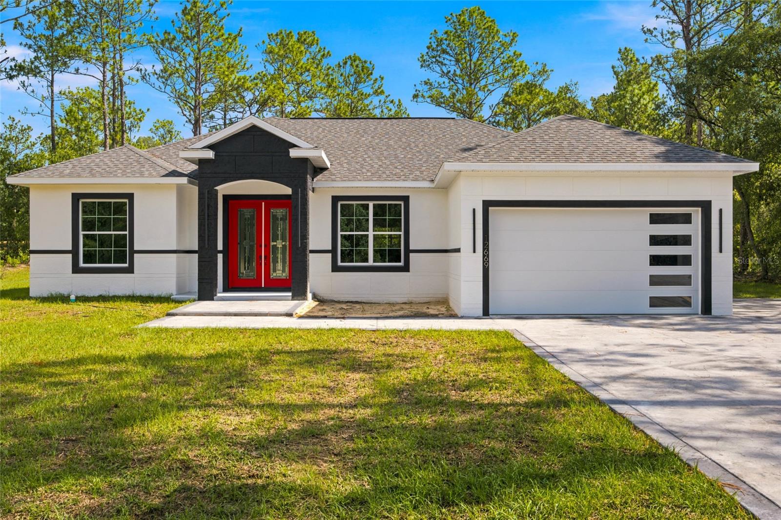 Welcome to this exceptional 4-bedroom, 3-bath custom home tucked away in a peaceful area of Dunnellon, offering over 2,700 total square feet, 2,011 living square feet, and situated on an impressive 1.12-acre lot. From the moment you arrive, this home makes a bold and memorable first impression with its crisp cream exterior, striking charcoal trim, and standout red front door that adds the perfect touch of character and curb appeal. The upgraded stamped and painted concrete driveway features finished borders and extends along the side of the home, providing additional parking space and everyday convenience.
Inside, the attention to detail is immediately apparent. This thoughtfully designed split floor plan offers 4 spacious bedrooms, 3 full bathrooms, Luxury Vinyl flooring throughout, and elegant custom finishes that create a bright, modern, and high-end feel. The main living area is beautifully accented by cream and gold coffered ceilings, adding depth, sophistication, and architectural charm while perfectly complementing the home’s overall design.
The kitchen is a true centerpiece, blending luxury, function, and timeless style. Designed to showcase the natural beauty of the granite countertops, the kitchen features hidden outlets that preserve the clean, uninterrupted look of the stone. Cream color cabinetry with gold hardware, a gold faucet, and a stainless steel farmhouse-style sink create a refined and cohesive aesthetic. The elegant gold-painted vent hood adds a stunning focal point, tying beautifully into the cream and gold ceiling details. A cream refrigerator, stainless steel appliances, modern light fixtures, and matching gold accents throughout the kitchen and dining areas complete the space with a polished designer feel.
The thoughtful upgrades continue throughout the home. Each bathroom carries the same elegant aesthetic as the kitchen, featuring coordinated cabinetry, stylish finishes, and LED-lit mirrors that add both function and a modern touch. The laundry room is equally impressive, offering matching cabinetry, matching granite, and a sink that brings convenience and style together seamlessly.
The primary suite offers comfort, privacy, and elevated design, featuring a spacious layout, an upgraded walk-in closet, and a spa-inspired bathroom with a beautiful double vanity and carefully selected finishes that continue the home’s cohesive style. Every detail has been chosen with intention, creating a home that feels custom, elegant, and truly move-in ready.
Even the garage has been upgraded with epoxy-coated floors and a modern garage door featuring stacked windows along the right side, giving the space a clean, finished, and contemporary look.
Beyond the home itself, the location offers the best of both worlds far enough away to feel peaceful and private, yet close enough to everyday conveniences. Located just a short drive from Rainbow Springs, the World Equestrian Center, grocery stores, shopping, dining, and more, this property offers privacy, style, space, and accessibility in one impressive package.
This is more than just a home  it is a true custom showpiece with bold curb appeal, elegant finishes, and thoughtful upgrades throughout. Schedule your private tour today.