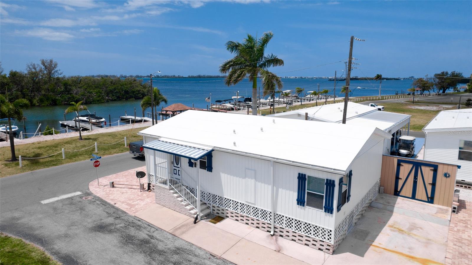 Don't settle for just a "water view", when you can have "water frontage", directly on Sarasota Bay AND have the unobstructive view to enjoy those majestic sunsets without leaving home.  This 2 Bedroom, 2 Full Bath Jacobson home comes turnkey furnished for the convenience of moving right in after taking ownership! Outside in the front of your home, the newer pavers add space for extra parking, ready to become the foundation to add a raised deck for keeping an eye on the manatees & dolphins that frequent between the mangroves & docked boats. In the rear of the home, 2 full size parking areas makeup the driveway. Great place to add an overhang for a carport for your picnic table & bbq grill. (which is remaining along with a covered love seat swing with canopy.) Extra storage comes with a large shed complete with a window for air circulation & downspouts for directing the rain away from the property, it is also securely anchored down for stability. New siding was installed throughout the exterior of the home along with navy blue custom shutters to promote that nautical look!. New lattice was added arounder the perimeter, which aids in air circulation. The roof was also just replaced during the renovation. Heading back inside, choose one of two entrances on either side of the home for your convenience. Enjoy granite counters in your kitchen along with a window over the sink to let natural light in while you're preparing your favorite recipe for your guests. Dining area is right off of the kitchen which joins the living room. Both stretch across the front of the home along with several windows to enjoy the scenery & catch a few boats going by or admire the variety of birds that frequent this area. Heading down the hall to the bedrooms, you'll come upon bifold doors which store your full-size washer & dryer. Continuing down the hall, you'll be at your guest bath with a full shower.  Guest room & primary bedroom are a generous size, complete with ample closet space. The primary is ensuite. Paradise Bay is a very desirable 55+ community, complete with boat slips available for rent along with boat storage on the premises for those that prefer to store their vessel out of the water. The boat ramps are conveniently located throughout the community for ease of launching your watercraft, kayaks & jet skis. Ramps are private & just for residents of the park. This is a very friendly park with scheduled activities & entertainment, just check the schedule at the clubhouse. Enjoy tennis, bocce ball, pickle ball & shuffleboard for some friendly competition. If you choose to venture out, Anna Maria Island is a quick drive on Cortez Rd. Only about 5 minutes until your toes are in the powdery soft sand searching for beautiful shells along the coastline. Restaurants are in abundance throughout Bradenton, along with grocery stores, houses of worship & shopping. For sports enthusiasts, golfing, fishing, hiking, parasailing, biking, recreational parks & even boating charters. Three airports, from a quick 15 minutes away to just under an hour away. Come & see for yourself, and make this bayfront, unobstructed view home your new address!