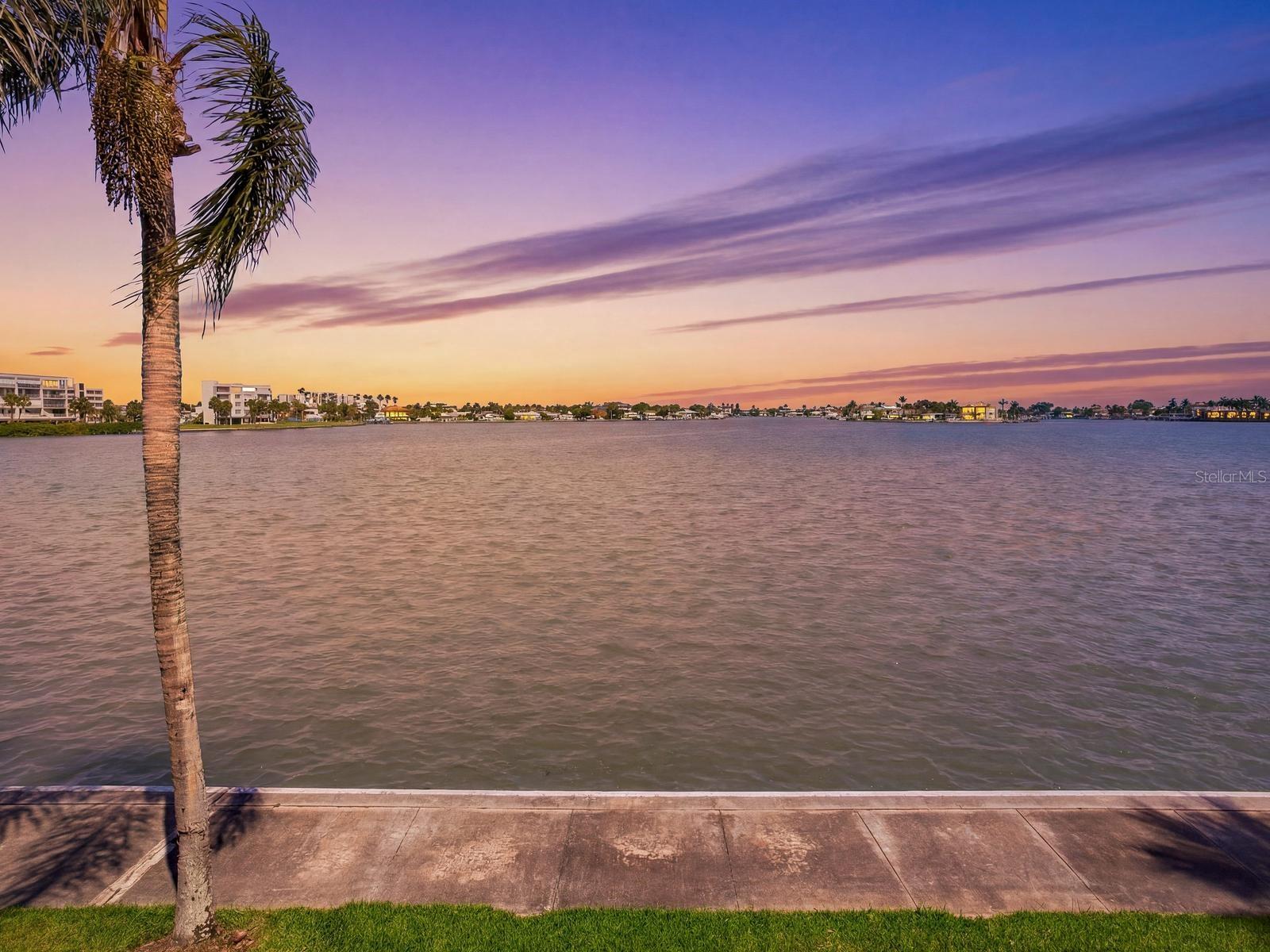 Experience upscale waterfront living at its finest in this fully remodeled 2-bedroom, 2-bath condo, perfectly positioned on the second floor with breathtaking Intracoastal views. Renovated in 2023, this light-filled residence showcases a stunning designer kitchen featuring an accent tile wall, updated appliances, bar seating, and seamless sightlines to the living and dining areas—ideal for both everyday living and entertaining. The bright, open living space is enhanced by elegant white poplar tongue-and-groove ceilings, modern fixtures, and panoramic water views where dolphins frequently make an appearance. Hurricane-rated windows and sliding glass doors, storm shutters, an in-unit washer and dryer, and dedicated ground-floor storage add comfort and peace of mind. The luxurious primary suite offers sweeping waterfront views, a custom walk-in closet, and a built-in safe. Its spa-inspired bath makes a striking statement with rich green tile and sophisticated designer finishes. Located within a sought-after 55+ gated community, residents enjoy resort-style amenities including a pool, tennis and pickleball courts, and a scenic walking path along the water. Move-in ready and beautifully updated from top to bottom, this exceptional condo boasts one of the community’s most desirable views—complete with unforgettable Gulf sunsets from your private balcony.