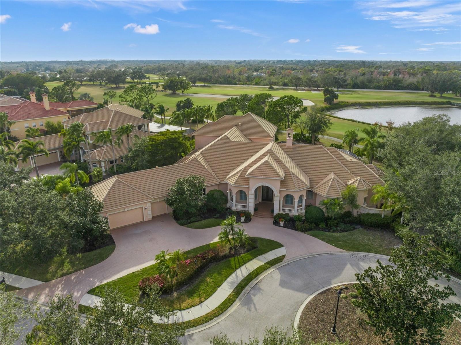 Experience the luxury in a breathtaking enclave in University Park, a home perfectly perched in a serene setting at the end of a quiet cul-de-sac. This residence boasts stunning lake views, proximity to the Clubhouse, and direct views of the 9th and 18th fairway. Every aspect of this home was meticulously crafted: generous proportions, superior construction, exquisite selection of materials, cutting-edge appliances, & advanced automation systems.  As you step through grand double doors of wrought iron and glass, through a majestic foyer with soaring ceilings leading into a 17X14 music room, and the formal living room, with inviting vistas of the expansive lanai and sparkling pool and spa. Culinary artists will revel in the chef's dream kitchen, equipped with elite Dacor, Wolf and Subzero appliances. Features include carved wood cabinetry, elegant stone counters, a prep sink, wine cooler, and a spacious pantry that is both functional and elegant. Indulge in the serene luxury of the primary bedroom suite, showcasing stunning built-ins, a cozy sitting area ideal for indulging in a captivating book or gazing at the tranquil lake, complemented by two spacious walk-in closets and an elegant dressing area.  The stunning en-suite bathroom is drenched in natural light. An open/split floor plan provides three additional bedrooms, each featuring ample closet space, 2 additional bathrooms, and an office/study complete with built-ins and picturesque views of the 9th fairway, all conveniently located on the first level. Venture to the second floor for a media room, game room, an additional bedroom and another full bathroom, providing a perfect retreat for both relaxation and entertainment. Sliding glass doors seamlessly connect the living room, primary bedroom, great room and study to the fabulous outdoor area: a shimmering pool and spa, a covered area with outdoor kitchen and fireplace, with a large area for sunbathing in complete privacy.  For convenience, there's a half bathroom with washer and dryer, plus an outdoor shower to refresh after a delightful swim. A/C is approximately 6 months old.  Please note there is a minimum social membership.