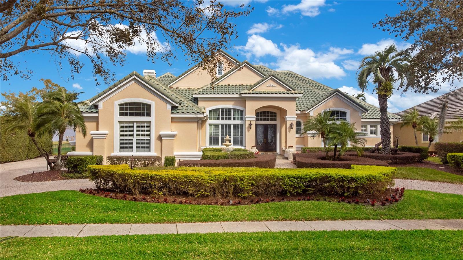 Take a look at this rare opportunity to own this custom lakefront estate in the guard gated neighborhood of Phillips Landing in Dr. Phillips. Be ready to be captivated by the panoramic breath taking lake views from the moment you enter this one level five-bedroom, five full bathroom pool home just under 5,000 heated square feet with a 3 car garage. This west facing home has a stately curb appeal with its half-moon paver driveway and timeless Mediterranean architecture surrounded with lush, manicured landscaping. Upon entry you will immediately notice the “WOW” factor with vaulted ceilings above the formal living, spectacular views, and a dining room for those special occasions with an adjacent 50+ bottle wine cellar. The spacious open floor plan with soaring 14 foot ceilings offers the best living & entertaining with rooms adorned with Crema Marfil marble floors, elegant light fixtures, and breathtaking panoramic views of Big Sand Lake. The kitchen is fully equipped with solid wood cabinetry, Kitchen Aid commercial style stainless steel appliances, vented hood, premium quartzite counter tops, center island, breakfast bar, and plenty of storage space. Your spacious primary bedroom suite boasts wood floors, a large portrait window, an enormous California style walk in closet, spa like bathroom with dual vanities, stone shower, and a jetted tub.  Secondary en-suite bedrooms are all spacious with their own closets and bathrooms. Invite your friends and family over for a game night in your own private great room/billiards room which includes a custom bar fully equipped with a beverage refrigerator and ice maker.  You will feel like you are on vacation when stepping out through the sliding glass doors leading to your private screened in oasis. The backyard was designed for entertaining and gathering around the pool, dining under the lanai, barbecuing from the summer kitchen, or just relaxing in your large pool and spa. There is plenty of space in the backyard to enjoy the lake with over 115 feet of pristine shoreline. Big Sand Lake offers you an amazing lake lifestyle to enjoy over 1,000 acres of spring fed lake including skiing and fishing activities. The sellers are putting in a brand-new dock for you at their own expense. Permit has already been approved and the construction of the new boat dock with lift is underway. Phillips Landing is 24-hour man gated, includes a park, playground, short distance to the famous Dr Phillips Restaurant Row, shops, Trader Joe’s, Publix, Whole Foods, golf courses, areas parks & attractions, airport, and great schools. Don’t miss out on this extraordinary lakefront property waiting for you. Be sure to click on the virtual tour links. 

<iframe width='853' height='480' src= https://my.matterport.com/show/?m=pxX8k9tMrDA&mls=1
></iframe>