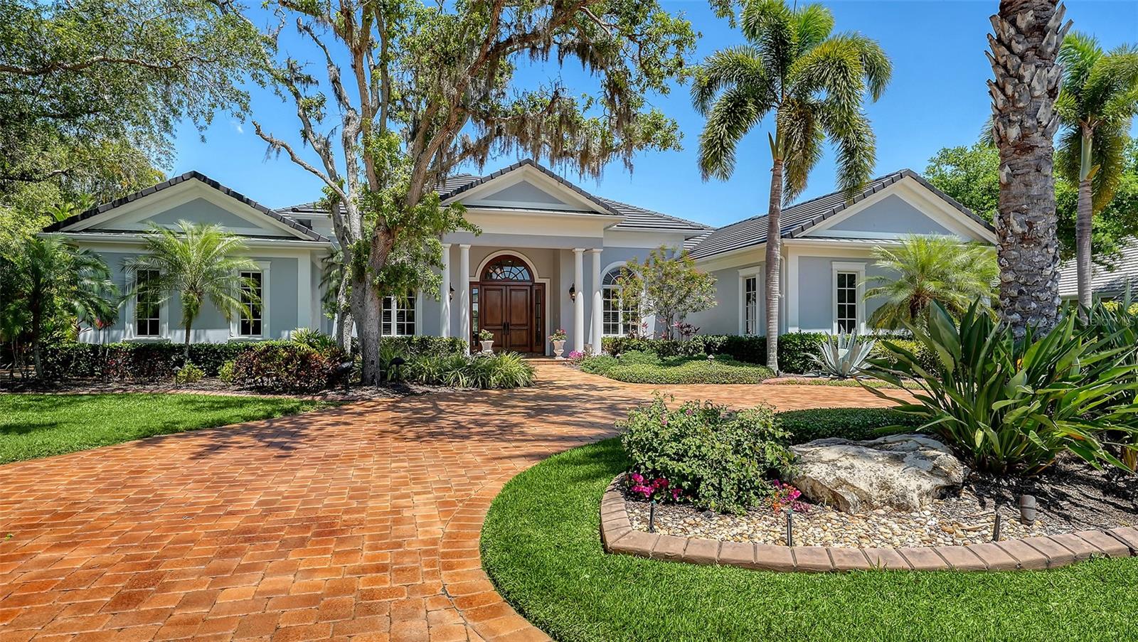 A custom-built Baron estate of timeless elegance, overlooking a tranquil lake from a quiet cul-de-sac within one of the region’s most coveted guard-gated communities. Located in Oaks Bayside, oak-canopied streets, private bay access, and a peaceful setting define everyday living—just steps from the community’s private day dock on Little Sarasota Bay for kayaking and sunset views.
Offering 5,287 square feet of living space, the home features four bedrooms, an office, a study, and 3½ baths, with a floor plan designed for both refined entertaining and comfortable living. Travertine marble and rich hardwood floors extend beneath coffered and tray ceilings, while aquarium windows and impact glass fill the interiors with natural light and frame serene lake views. A gas fireplace anchors the living room, and surround sound enhances the main living areas, all flowing seamlessly to the screened lanai.
The chef’s kitchen is appointed with Wolf and Sub-Zero appliances, an oversized island with bar seating, and a walk-through pantry. A casual dining area adjoins the kitchen, while a separate formal dining room accommodates more formal gatherings. A wet bar with a large-capacity wine refrigerator and custom cabinetry adds a sophisticated entertaining element.
The primary suite offers a private sitting area and a luxurious bath with separate vanities, individual dressing areas, private water closets, and two walk-in closets with custom built-ins. Three additional bedrooms are thoughtfully positioned for family or guests, along with a spacious office, separate study, and a five-seat home theater.
Outdoors, the expansive screened lanai is designed for year-round living, featuring a pool, spa, fountain, covered seating, and a full outdoor kitchen overlooking the lake and lush tropical landscaping. An elegant circular paver drive and a three-car garage with epoxy floors and extensive storage enhance both form and function.
Additional highlights include a whole-home vacuum system, solid wood doors, impact windows, a cedar closet, and abundant storage throughout. Located in Flood Zone X for added peace of mind.  The Oaks Country Club offers 2 championship 18 hole golf courses,
Tennis, pickleball, croquet, bocce, and an abundance of social activities to stay engaged in all the club has to offer. 
Ideally located near downtown Sarasota, Siesta Key Beach, and renowned cultural destinations, Oaks Bayside offers a rare blend of privacy and convenience. Membership to The Oaks Club is required. A wonderful opportunity to live in one of the finest country clubs in Florida.