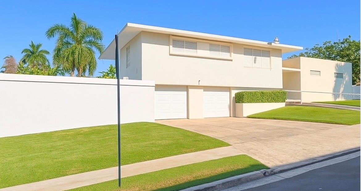 Located in Garden Hills Norte, one of the most prestigious and well-established communities in Guaynabo and the greater metropolitan area, this spacious three-level residence offers exceptional potential for remodeling, value appreciation, or creating a remarkable family home. The first level features a large patio and pool area surrounded by generous green space wrapping around the property, along with a versatile bonus room ideal for a gym, office, guest suite, or entertainment space. The home offers parking for up to four vehicles, including a front carport and two covered garage spaces. The second level, accessible from both the front entrance and the pool/patio level, serves as the main living area and showcases expansive open spaces with high ceilings, creating an airy and inviting atmosphere. This level also includes the largest bedroom in the home, complete with a spacious walk-in closet and oversized bathroom. The third level features four additional bedrooms, including the primary suite with its own private bathroom, while the remaining bedrooms share a large hallway bathroom. With its excellent layout, oversized spaces, and prime location, this property presents a tremendous opportunity for investors or buyers seeking to customize and elevate a home in one of Guaynabo’s most desirable neighborhoods.