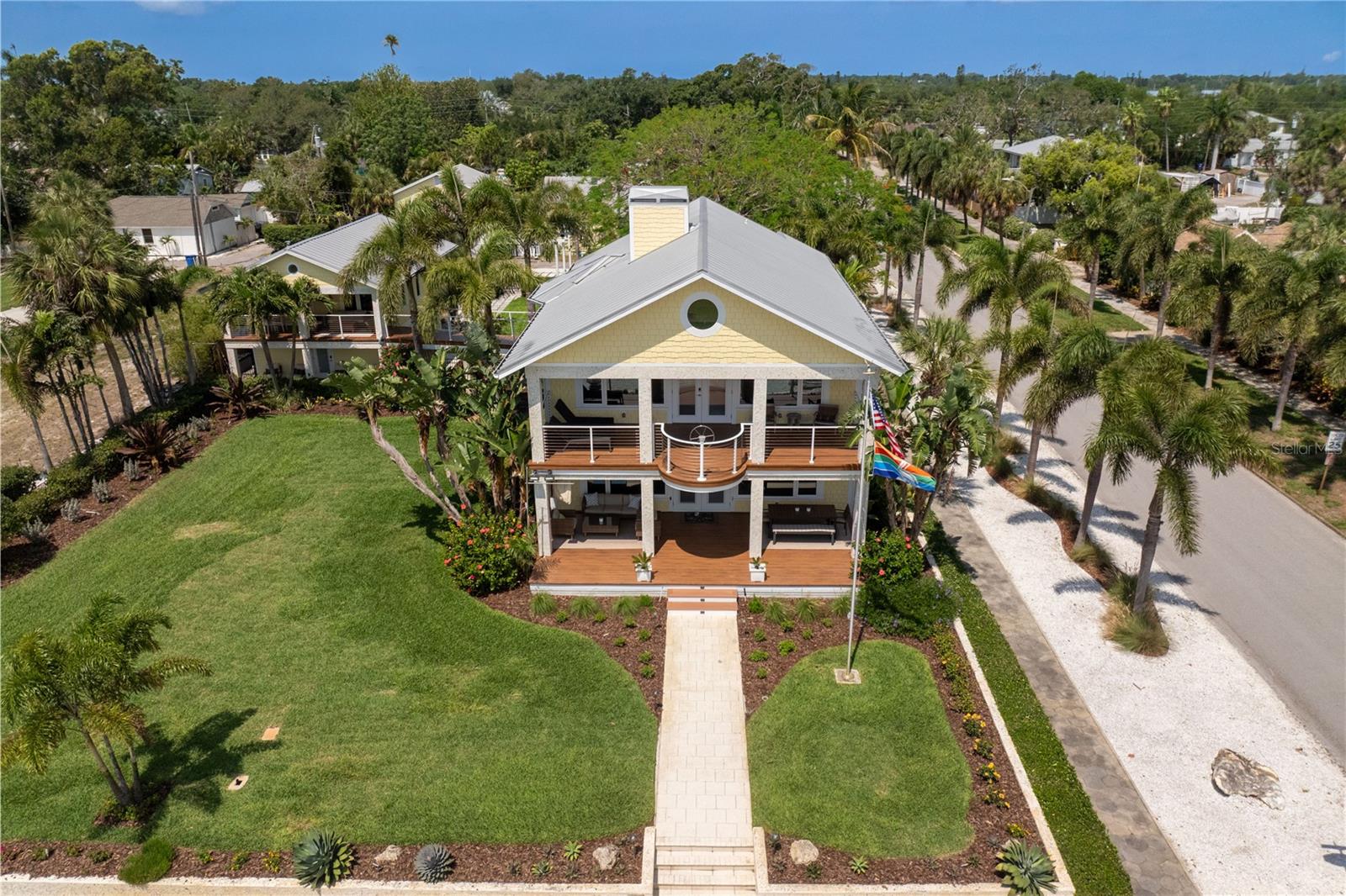 Set along one of St. Petersburg’s most treasured waterfront corridors, 1803 Beach Drive SE is a rare offering in Old Southeast, where historic architecture, open views of Tampa Bay, and the quiet beauty of Lassing Park come together in a way that feels almost impossible to recreate. Offered fully furnished and turnkey, the home presents an effortless opportunity to enjoy one of St. Petersburg’s most distinctive waterfront settings from day one. Originally built in 1915, the home has been extensively and thoughtfully renovated, preserving its architectural integrity while elevating it for modern coastal living. A cheerful exterior, metal roof, broad covered porches, tropical landscaping, and a detached guest house create an immediate sense of place. From the front lawn, porches, and main living spaces, the home looks directly across open green space to Tampa Bay, offering protected, uninterrupted views that define the property’s character.
The property is comprised of a three-bedroom main house, with each bedroom offering an en-suite bath, along with a half bath on the first floor. Thoughtfully updated while honoring its original character, the home balances historic warmth with a fresh, artful point of view. Original hardwood floors, crisp millwork, bright white walls, statement lighting, and generous windows create interiors that feel both refined and relaxed. The living and dining spaces are open, inviting, and filled with natural light, anchored by a brick fireplace and framed by views of the park and Tampa Bay beyond.
Upstairs, the expansive primary suite spans the front of the home, creating a private retreat with exceptional scale and presence. A large balcony faces the water, offering a peaceful place to take in sunrise views over Tampa Bay, watch the movement of the park below, or unwind in the evening above the treetops.
A second-story bridge leads from the main residence across the lush gardens to the detached guest house, creating a unique and memorable connection between the two living spaces. Upstairs, the guest apartment offers two bedrooms, one bath, and a full kitchen, providing comfortable accommodations for visitors, extended family, or private work-from-home space. On the first floor, a dedicated wine room sets the stage for entertaining, intimate gatherings, and game nights, while the converted garage now serves as a state-of-the-art fitness studio complete with a WaterRower, elliptical machine, and half bath.
The outdoor experience is equally compelling. Broad covered porches, expansive decking, tropical landscaping, and generous lawn space create a seamless indoor-outdoor lifestyle. From nearly every vantage point, the home enjoys a rare and protected view across open parkland to the waters of Tampa Bay.
Old Southeast has long been one of St. Petersburg’s most distinctive neighborhoods, known for its historic homes, creative spirit, front-porch lifestyle, and deep connection to the bay. Just minutes from downtown St. Petersburg, the location offers convenient access to the city’s restaurants, museums, galleries, waterfront parks, marinas, and cultural destinations, while still maintaining the quieter, residential feel that makes Old Southeast so special.