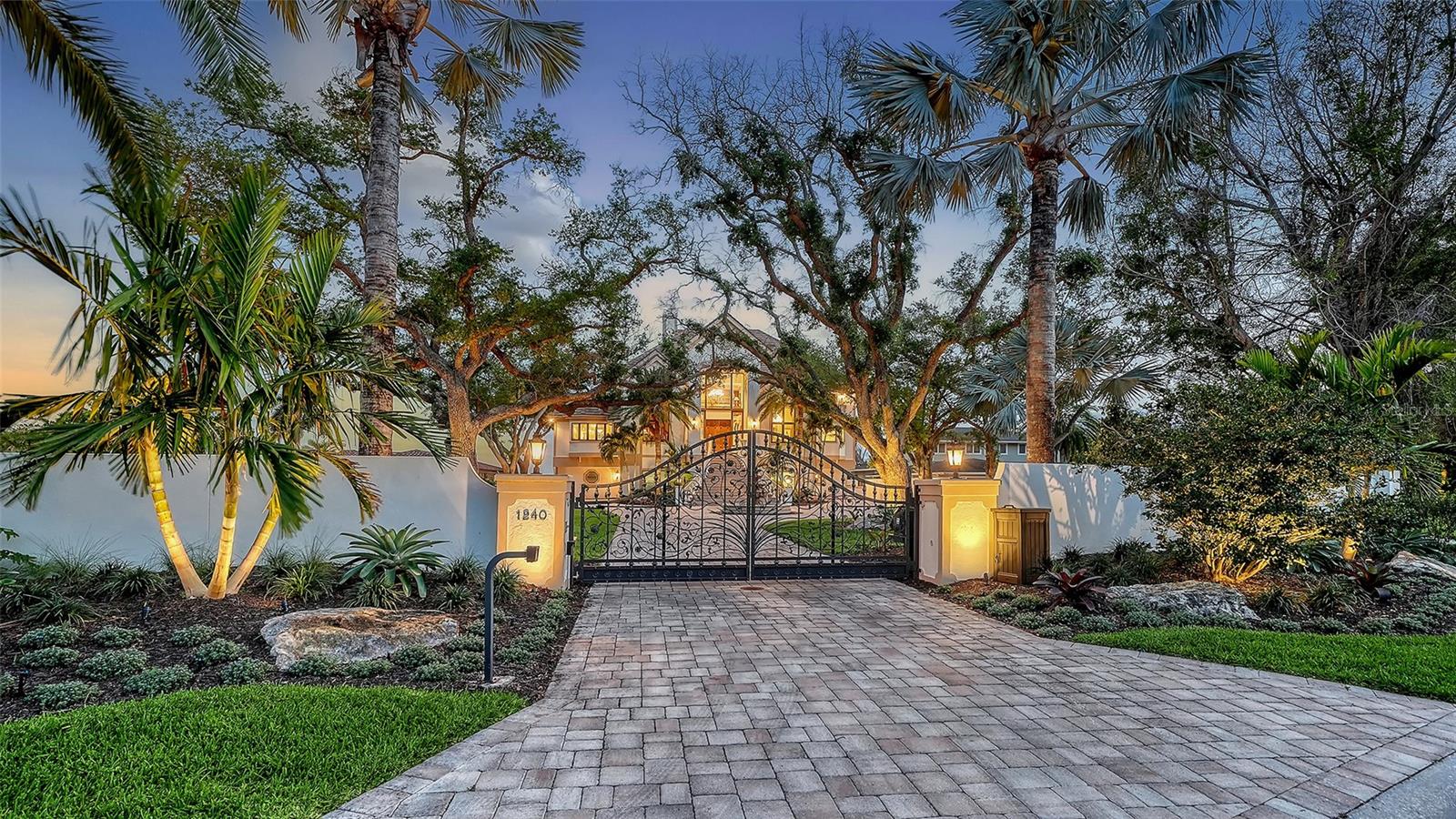 Introducing “Gatsby Manor,” set along Hillview Drive, one of Sarasota’s most coveted bayfront addresses, often compared to Port Royal for its exclusivity and waterfront lifestyle, this rare Harbor Acres estate property spans nearly three-quarters of an acre on deep, boatable water with sweeping, unobstructed Sarasota Bay views stretching south toward Siesta Key and the Gulf of Mexico, representing one of the neighborhood’s most distinguished open-bay offerings where only a select few residences achieve true estate scale. Encompassing more than 8,000 square feet of air-conditioned space with four bedrooms and three-and-a-half baths. The residence is complemented by a grand motor court accommodating 15+ vehicles beneath a canopy of majestic grand oaks. Privately approached through wrought-iron gates and a sweeping circular drive anchored by a multi-tiered fountain, the home opens to a dramatic two-story foyer framing the water beyond. Interiors are defined by soaring ceilings up to 22 ft. in height, exceptional millwork, multiple fireplaces, a striking two-story wood-paneled library, formal dining with 12-foot ceilings, and a wetbar—perfectly blending elegant entertaining with comfortable daily living. The chef’s kitchen is designed to support both everyday living and large-scale gatherings, featuring double 36-inch Sub-Zero refrigerators with dual freezer drawers, two dishwashers, and a 60-inch Wolf gas range with six burners and infrared dual griddle. The owner’s suite occupies the entire east wing of the main living level, creating a private waterfront retreat complete with a gas fireplace, sitting area overlooking the pool and bay, dual walk-in closets, and a spa-inspired bath highlighted by a sculptural copper soaking tub, dual vanities, and a dedicated luxury makeup area. Upstairs, a second primary-style suite and two additional guest bedrooms are accessed via the grand staircase or three-stop elevator, offering privacy and flexibility for family and guests. The 3,800+ square-foot ground-level bonus area serves as the home’s ultimate entertaining environment, featuring a remarkable speakeasy lounge and an impressive 700+ bottle wine room. This expansive space functions as a true extension of the residence’s living experience—ideal for hosting gatherings, intimate evenings, or celebrations on a grand scale. Outdoor living is equally exceptional, centered around an expansive marble terrace surrounding the 25’ × 60’ heated saltwater pool with integrated sun shelf and spa. A brand new deep-water dock with a 20,000 lb. boat lift and seawall replaced in 2017 further enhance the property’s boating capabilities and long-term value. Additional highlights include hurricane-rated garage doors, elevator access to all three levels, a drive-through three-car garage, and extensive storage throughout. Perfectly positioned just a short stroll to Southside Village’s restaurants and boutiques, minutes from downtown Sarasota’s celebrated arts and cultural district, and only four blocks from Sarasota Memorial Hospital. Gatsby Manor offers a truly rare opportunity to enjoy estate-scale open-bay living with deep water, privacy, and exceptional walkability in one of Sarasota’s most prestigious waterfront neighborhoods.