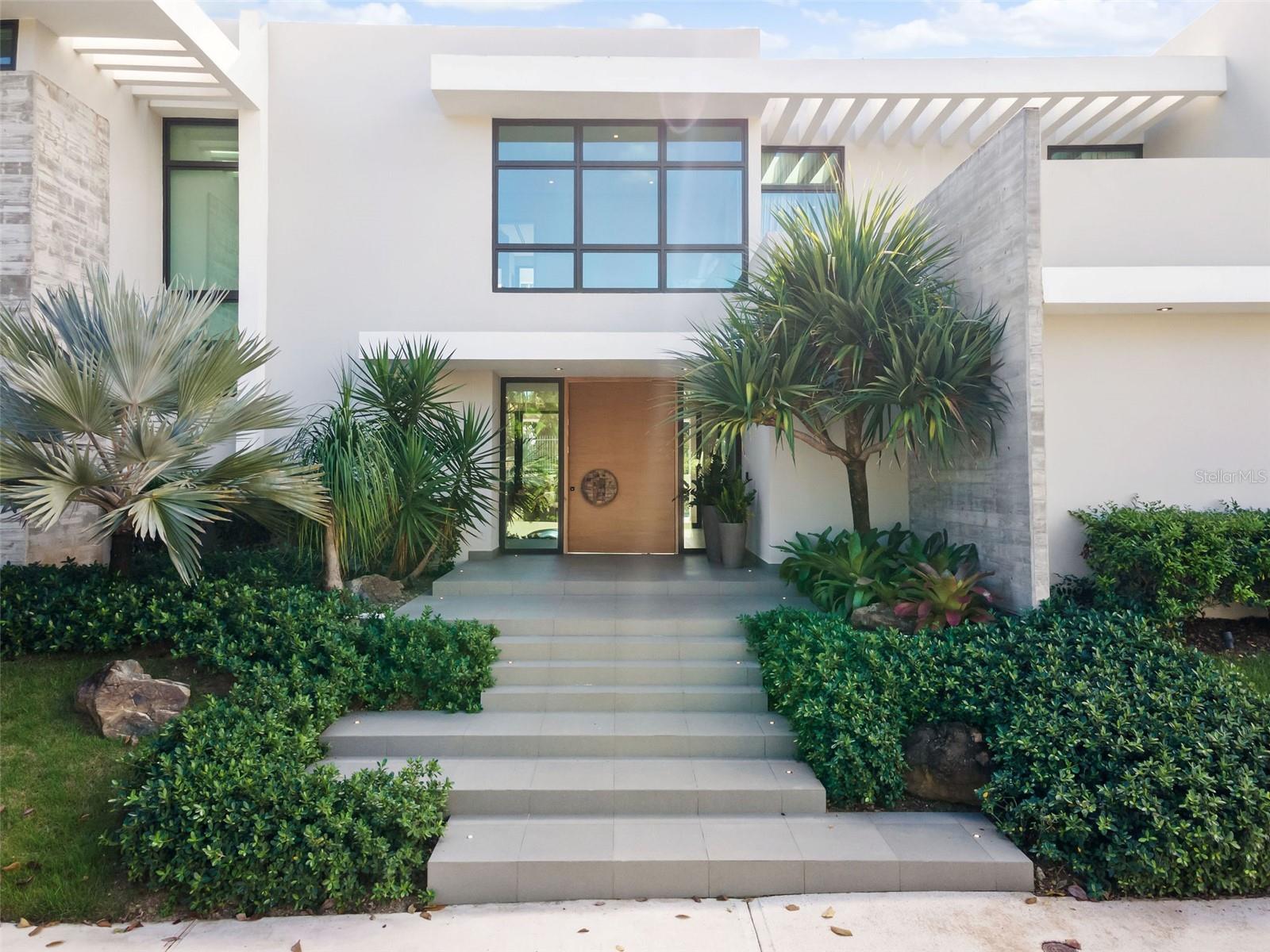 Located in Guaynabo’s exclusive Garden Hills North neighborhood, this impeccable home with close to 6,000 sqft of meticulously designed living space defines the concept of turnkey, ready-to-move-in perfection. Every inch of this masterpiece has been thoughtfully crafted with the utmost attention to detail by renowned interior designer, Gretchen Daubon. The renowned Jota Arquitects firm is responsible for the architectural genius at the rear of this house, which guarantees a tasteful fusion of style and utility.

This is a new construction that underwent a complete demolition and reconstruction, leaving no stone unturned in the pursuit of perfection. The 3-car garage offers ample space for your vehicles, with room to mount 3 more on top for the avid collector.

Upon entering, you'll be greeted by soaring high ceilings and sliding doors that effortlessly connect the opulent outdoor environment with the interior areas. Top-tier fixtures and finishes from Copat, an Italian brand known for luxury, adorn the kitchen, bathrooms, and closets. If you love hosting gatherings, you'll adore the dedicated entertainment area, featuring a billiard table, a chic wet bar, and a cozy living room, perfect for movie nights or karaoke parties.

Ascending to the second floor, you'll find a cozy sitting area leading to the grand master bedroom. The master suite has a lavish master bathroom with a beautifully designed his and hers vanity, an open shower, and an inviting bathtub. The master closet is expansive, offering ample space for all your belongings. Three additional generously-sized bedrooms, each with its own ensuite bathroom, complete this level.

Go outside to the beautifully designed patio, where you can unwind by the or take a dip or lounge in the pool. The terrace is a tranquil haven for alfresco dining and leisurely sitting.

This isn't just a house; it's a statement of luxury and sophistication. Every detail has been carefully chosen to offer the finest in high-end living. Don't miss the opportunity to own this luxurious piece of Garden Hills North.